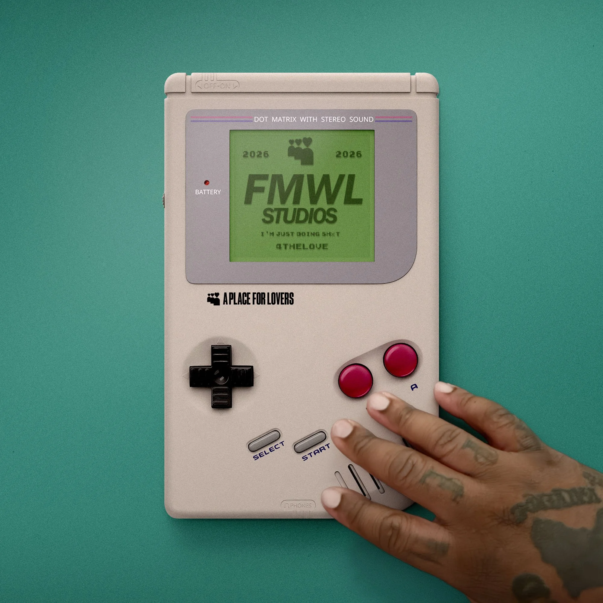 Close-up of a vintage handheld electronic game with a person’s hand resting on it, against a teal background. The game features a green screen, red buttons, a directional pad, and printed labels.