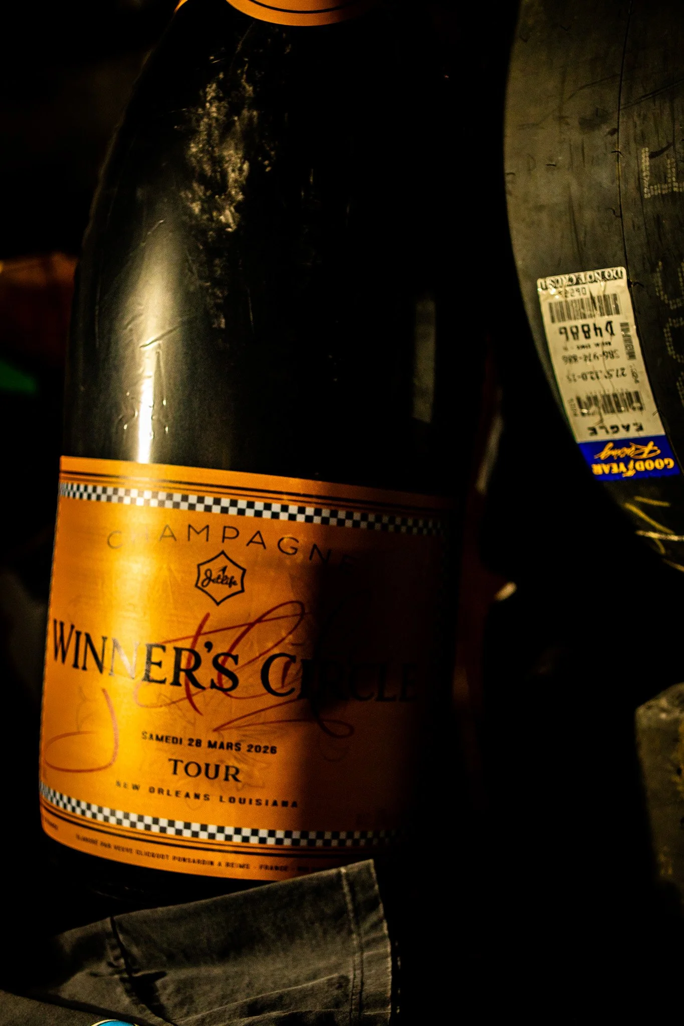 A bottle of Winner's Circle champagne from a tour in New Orleans, Louisiana, dated Saturday, March 28, 2026, with a partial view of another beverage bottle on the right.