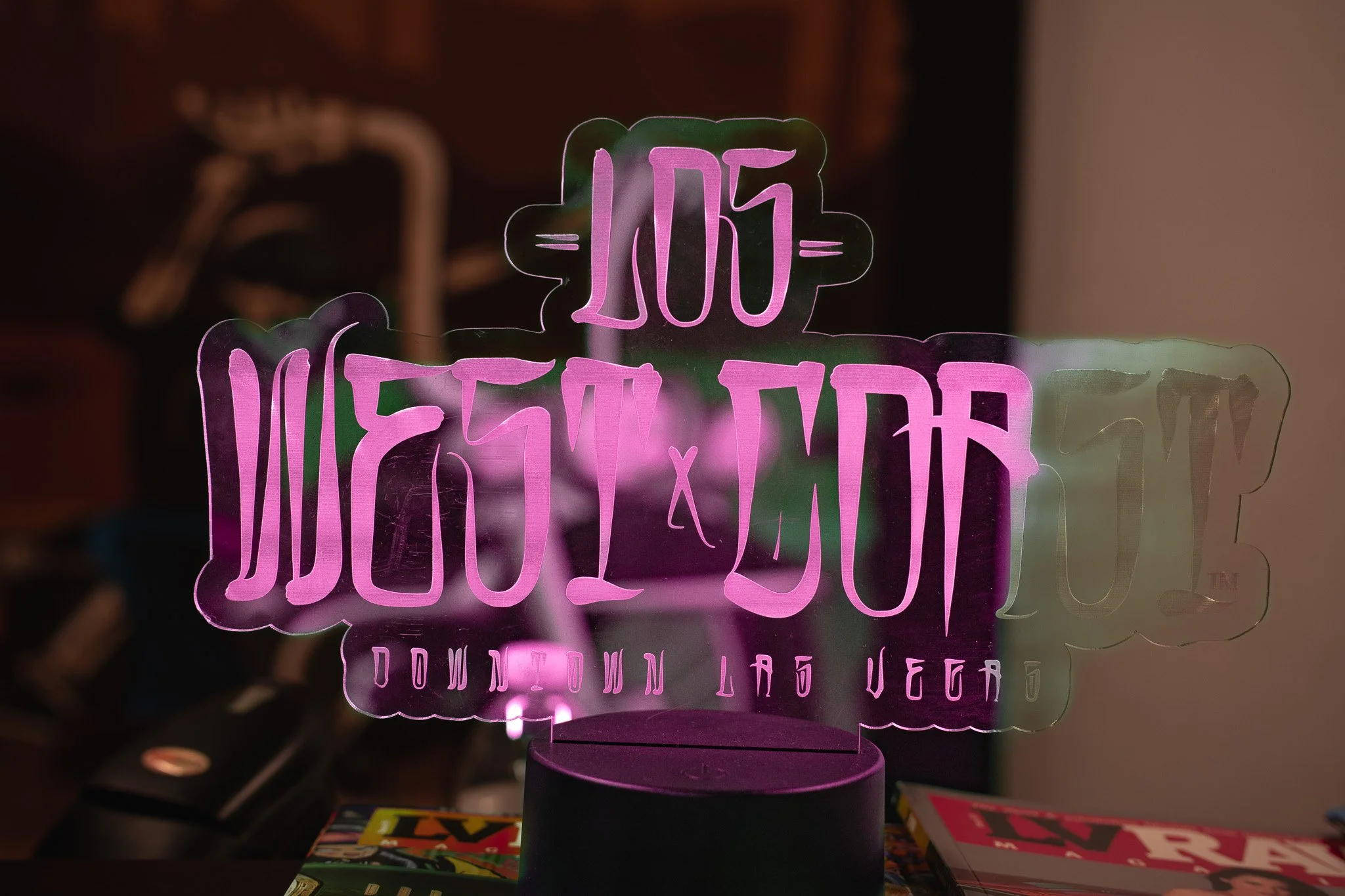 A neon sign that reads '105 Downtown Los Angeles' in pink and green colors, with a dark background.