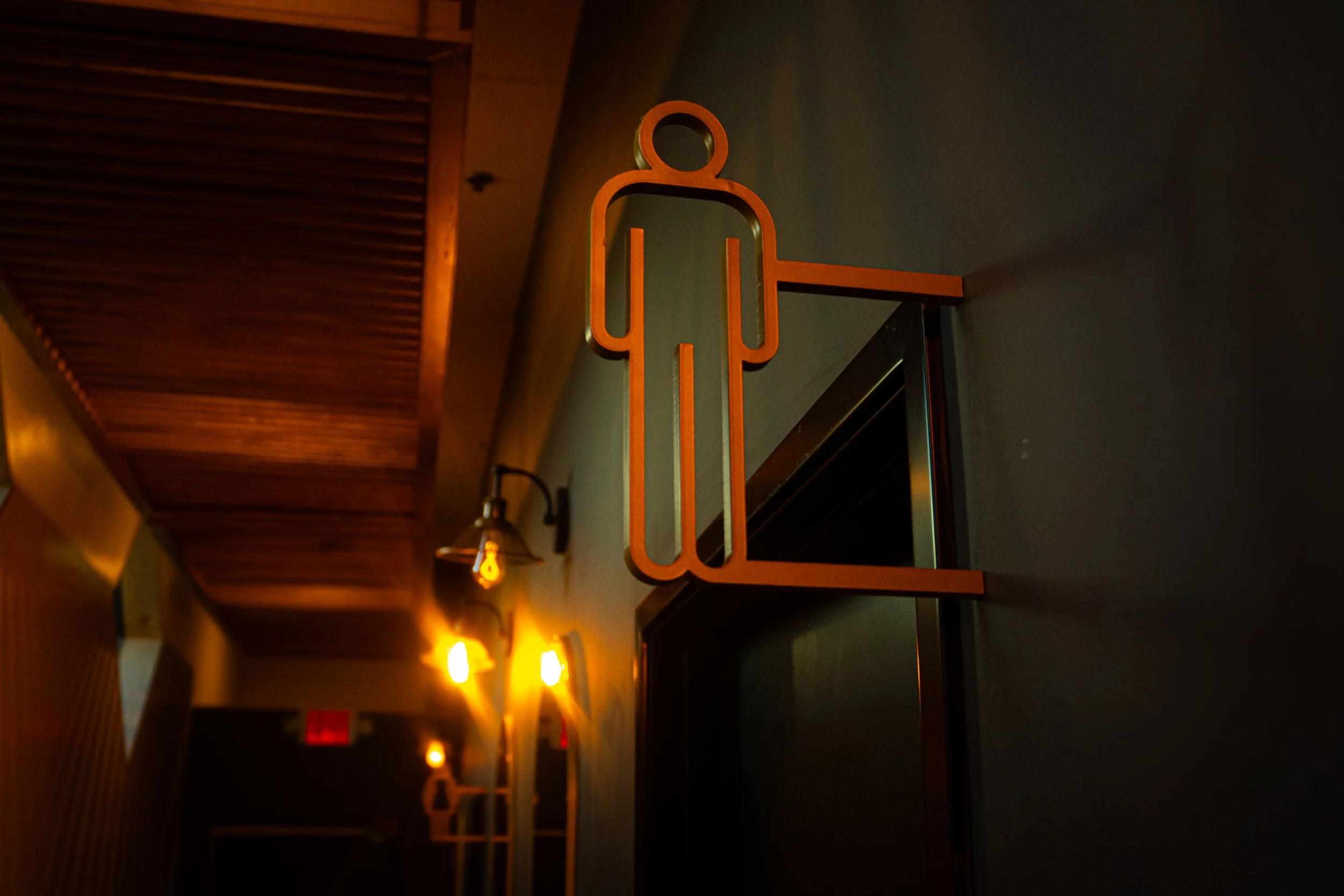 Wall-mounted wooden sign of a person, indicating a restroom or bathroom.