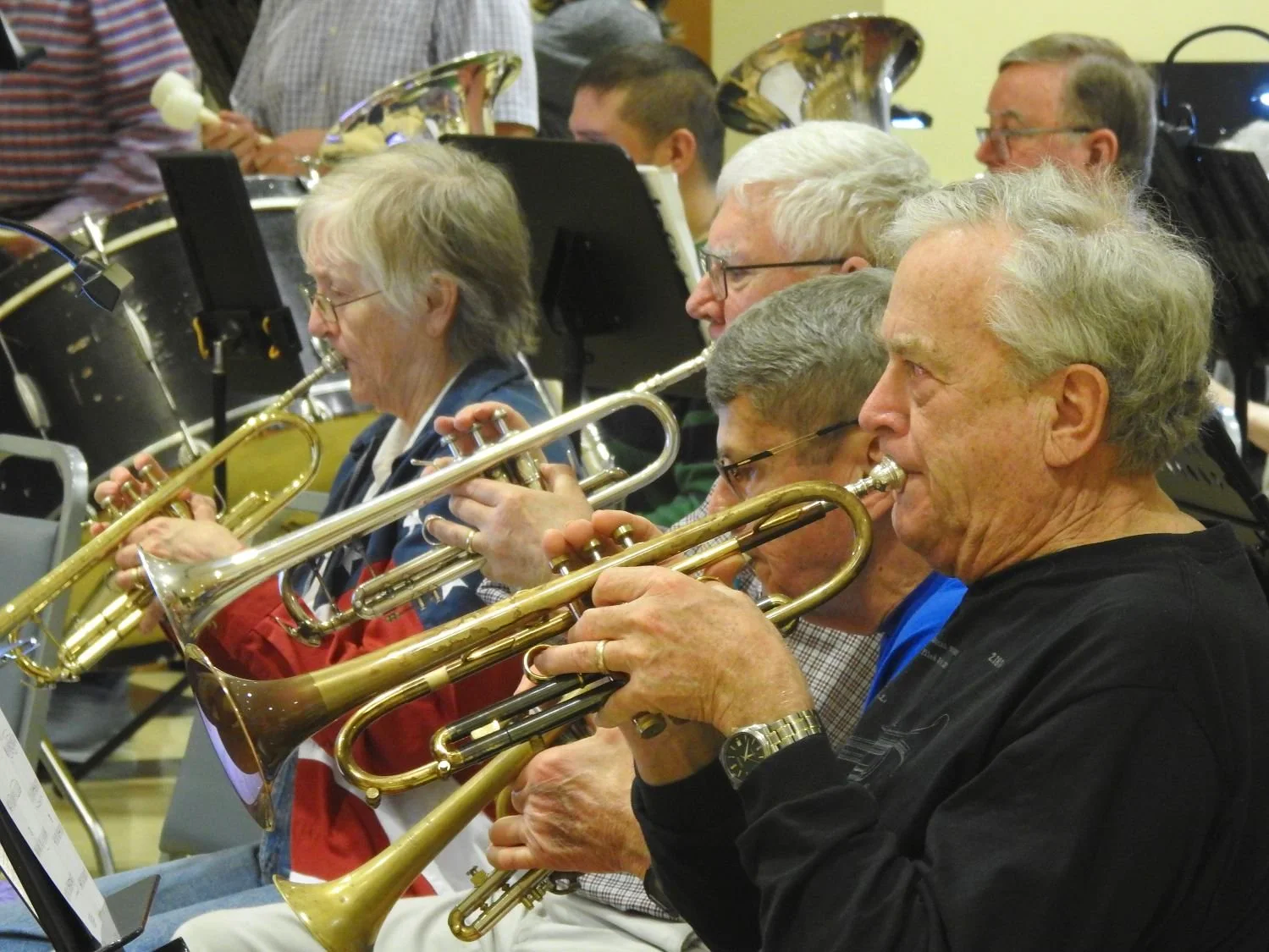Adults playing trumpets and percussion at a rehearsal New Horizons Band Austin Texas