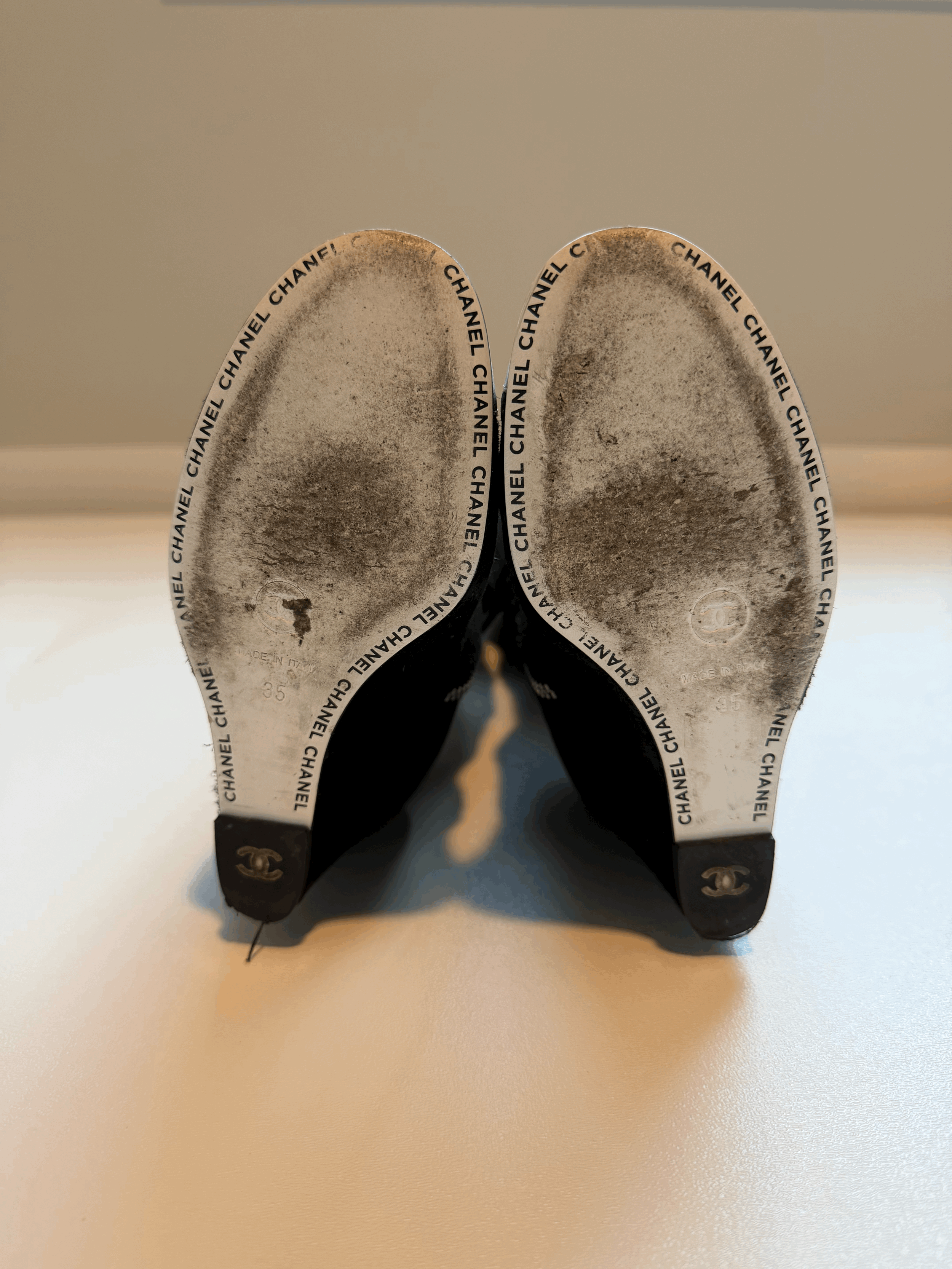 Up close view of black Chanel wedge boots outer sole. shows moderate wear and paint chipping