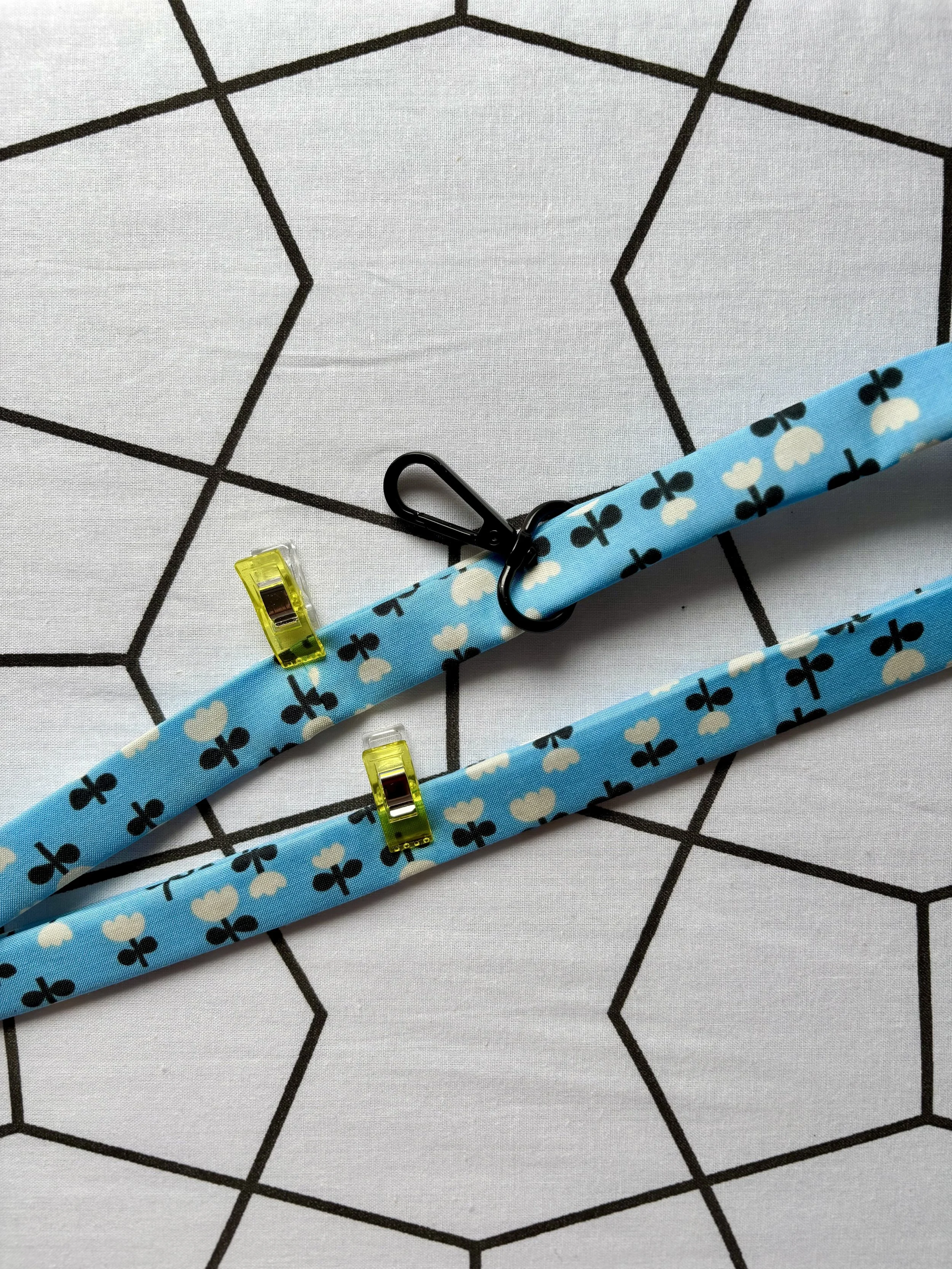 A photo of the pressed fabric of the lanyard clipped together with the hardware visible before stitching with an 1/8" seam allowance around the edges