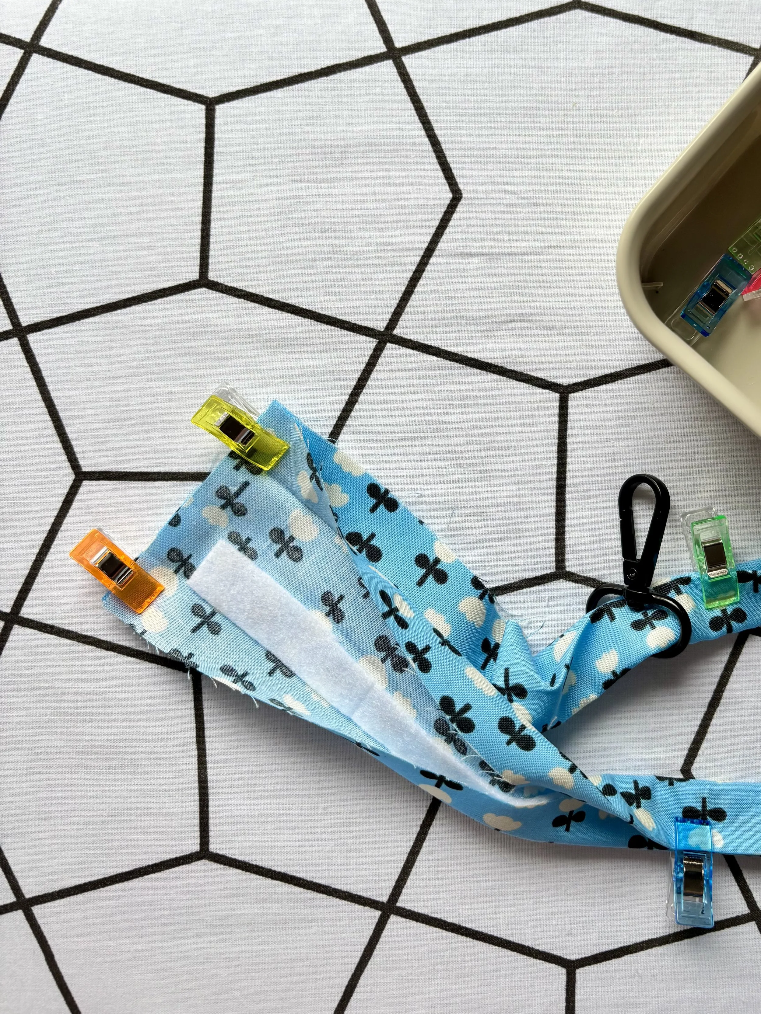 A photo of the right sides of the short ends of the fabric clipped together before stitching. You can see the hardware is looped through the fabric