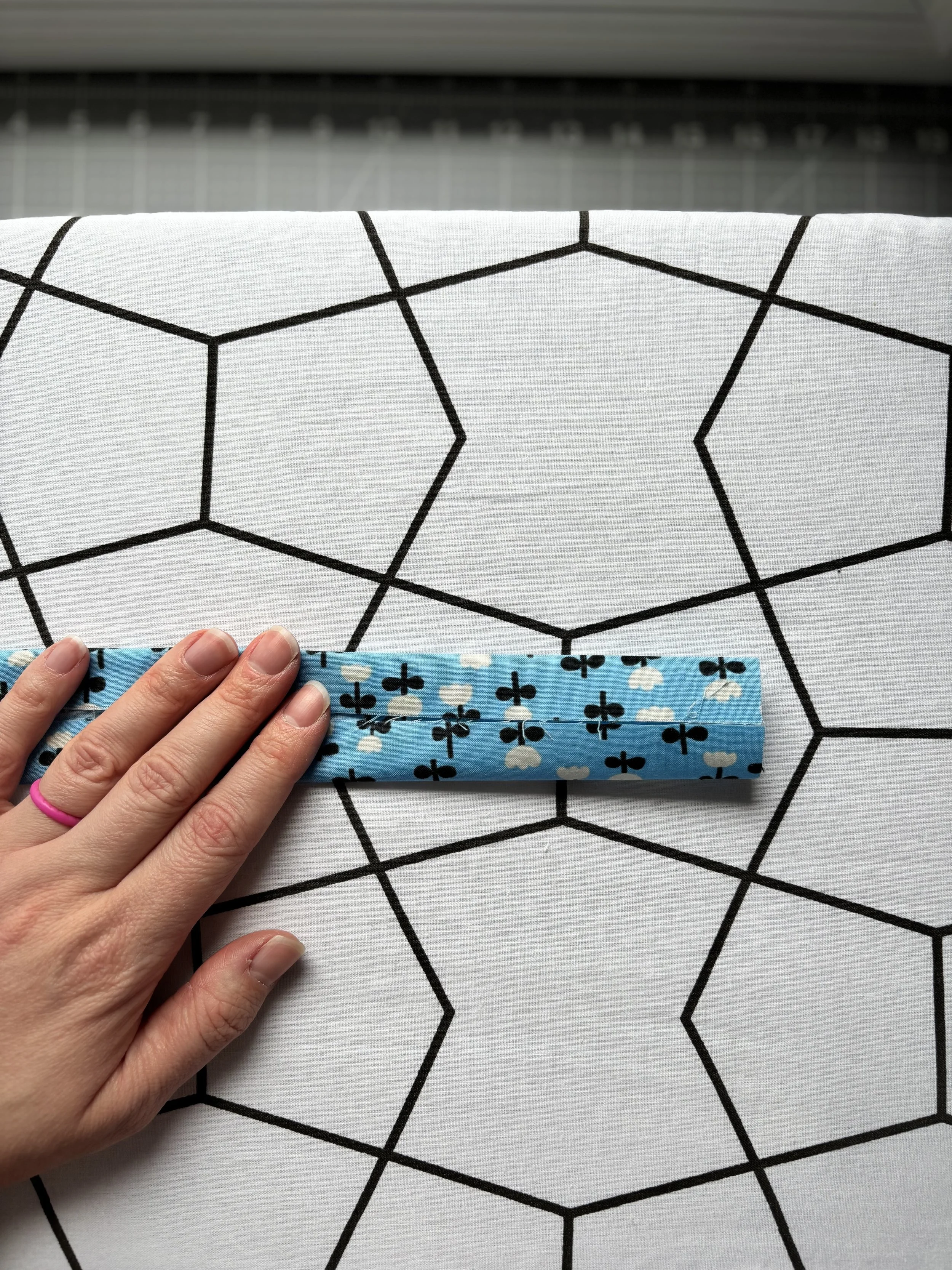 The fabric demonstrating how to press the fabric towards the centreline to incase raw edges.