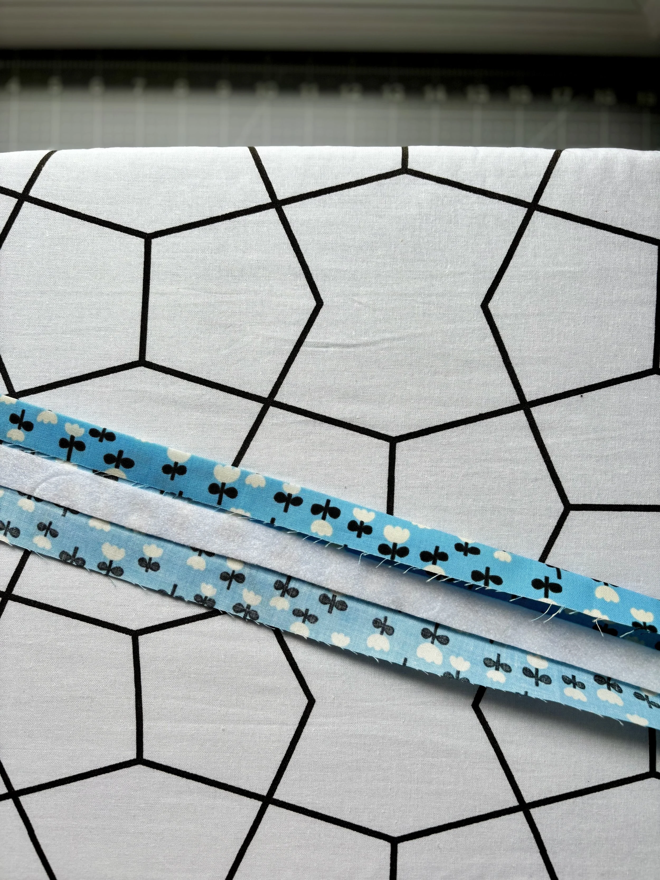 A photo of the fabric with the strip of fusible fleece attached to the fabric and one side pressed to the midline