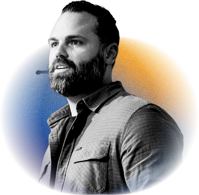 Black and white portrait of a man with a beard looking to the side, set against a graphic background with circles in blue, orange, and red.