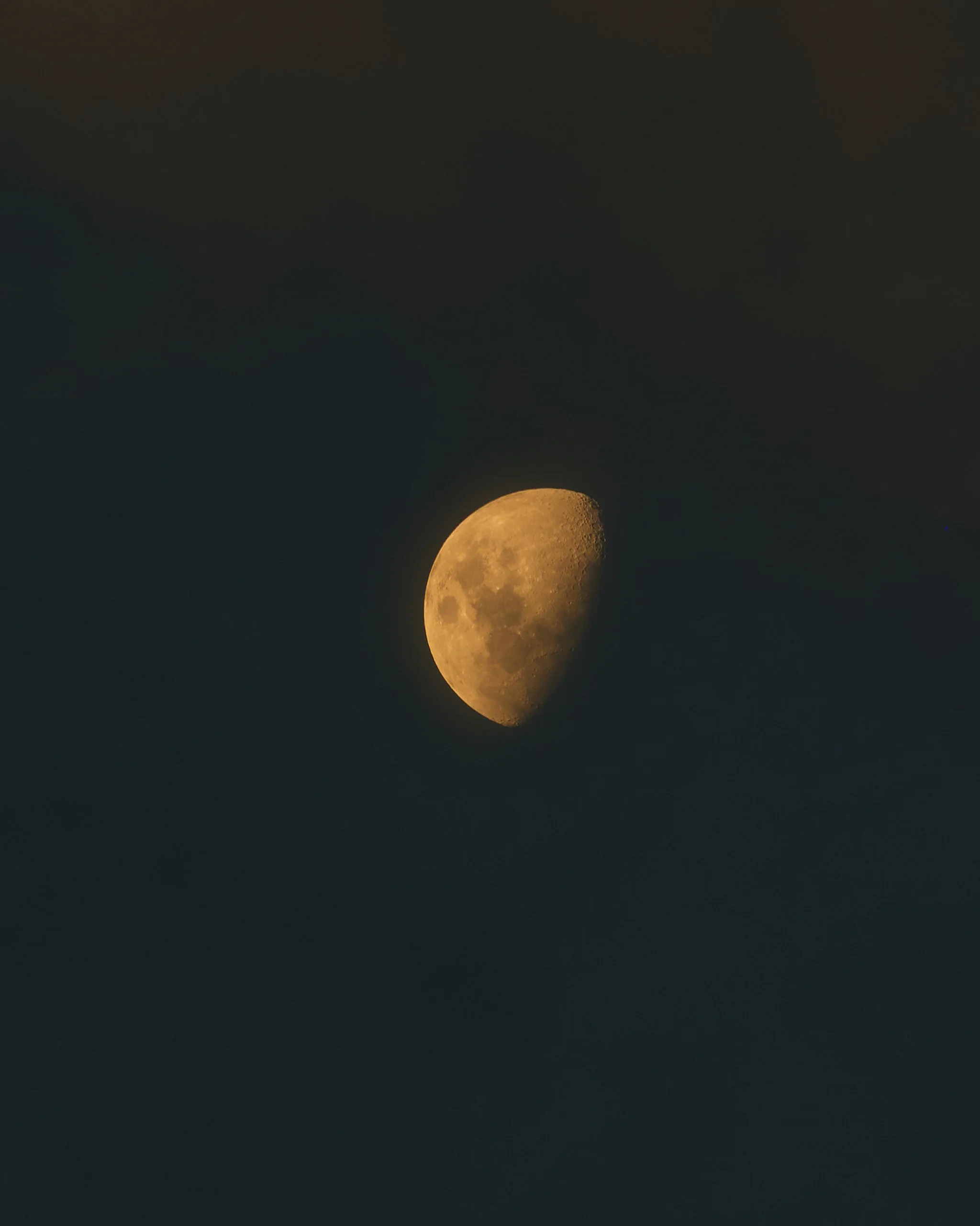 The moon in a waxing gibbous phase with a dark sky background.