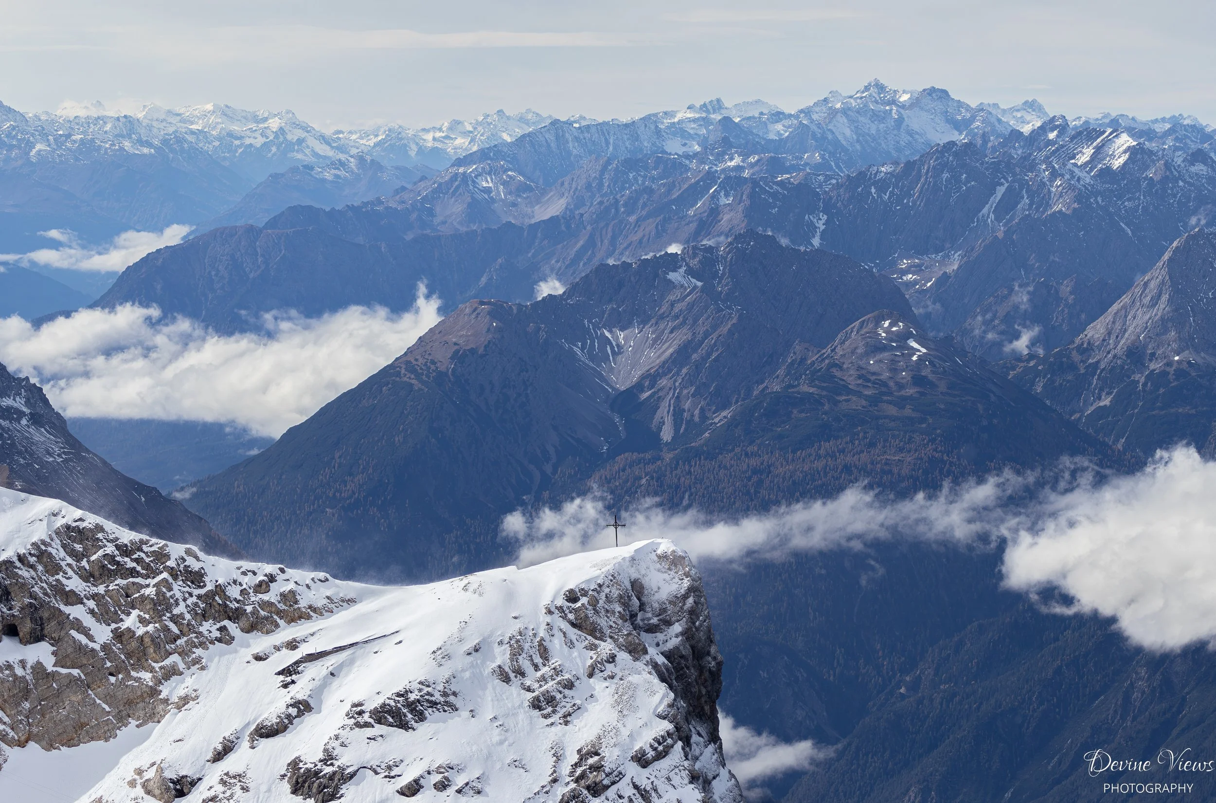 Panoramic view of snow-covered mountain peaks and rugged alpine ridges above drifting clouds