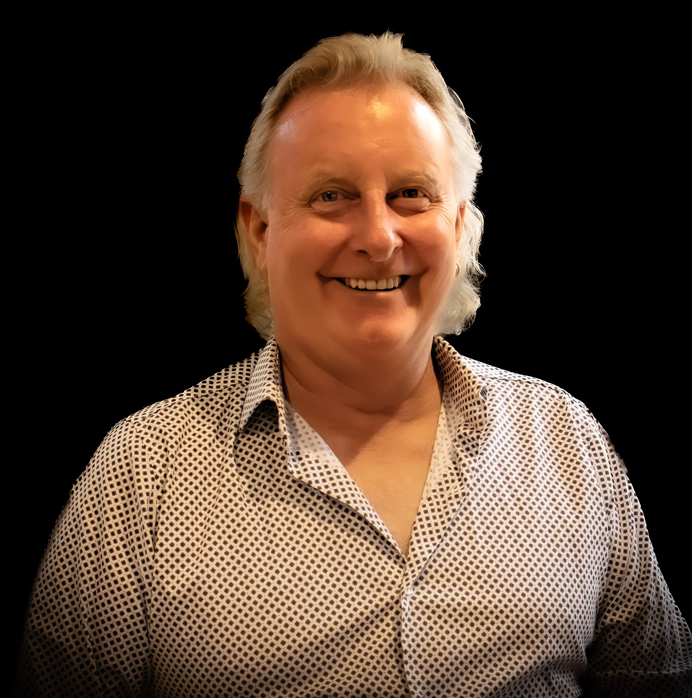 A man smiling, wearing a white shirt and a black background
