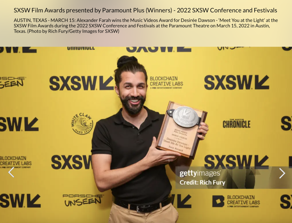 B.C.'s Desirée Dawson, Alexander Farah win SXSW award for best music video. Alex with beard and bun hairstyle smiling, holding an award plaque with a large coin attached, standing in front of a yellow SXSW backdrop with multiple logos and text.