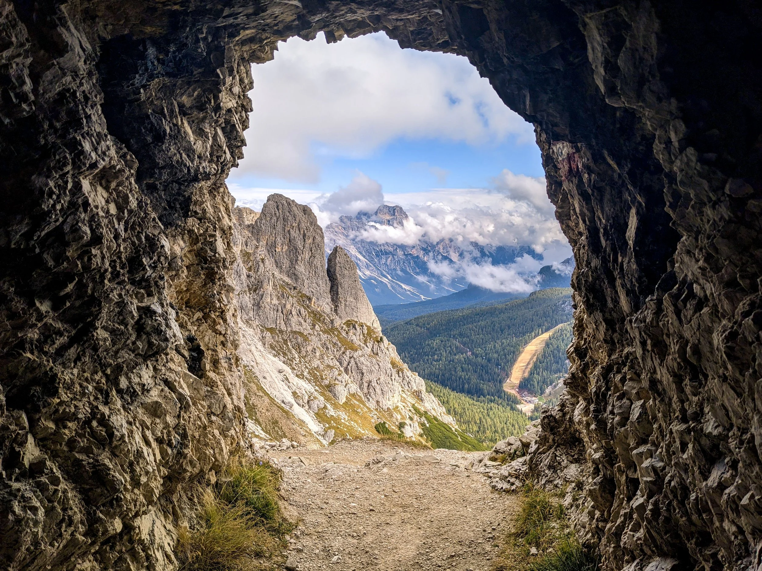 Sentinel's Watch
A moody and artistic night shot captured through a natural rock opening or bunker window. The dark, jagged silhouette of the frame creates a powerful contrast against the moonlit mountain peaks and the deep indigo of the night sky. T