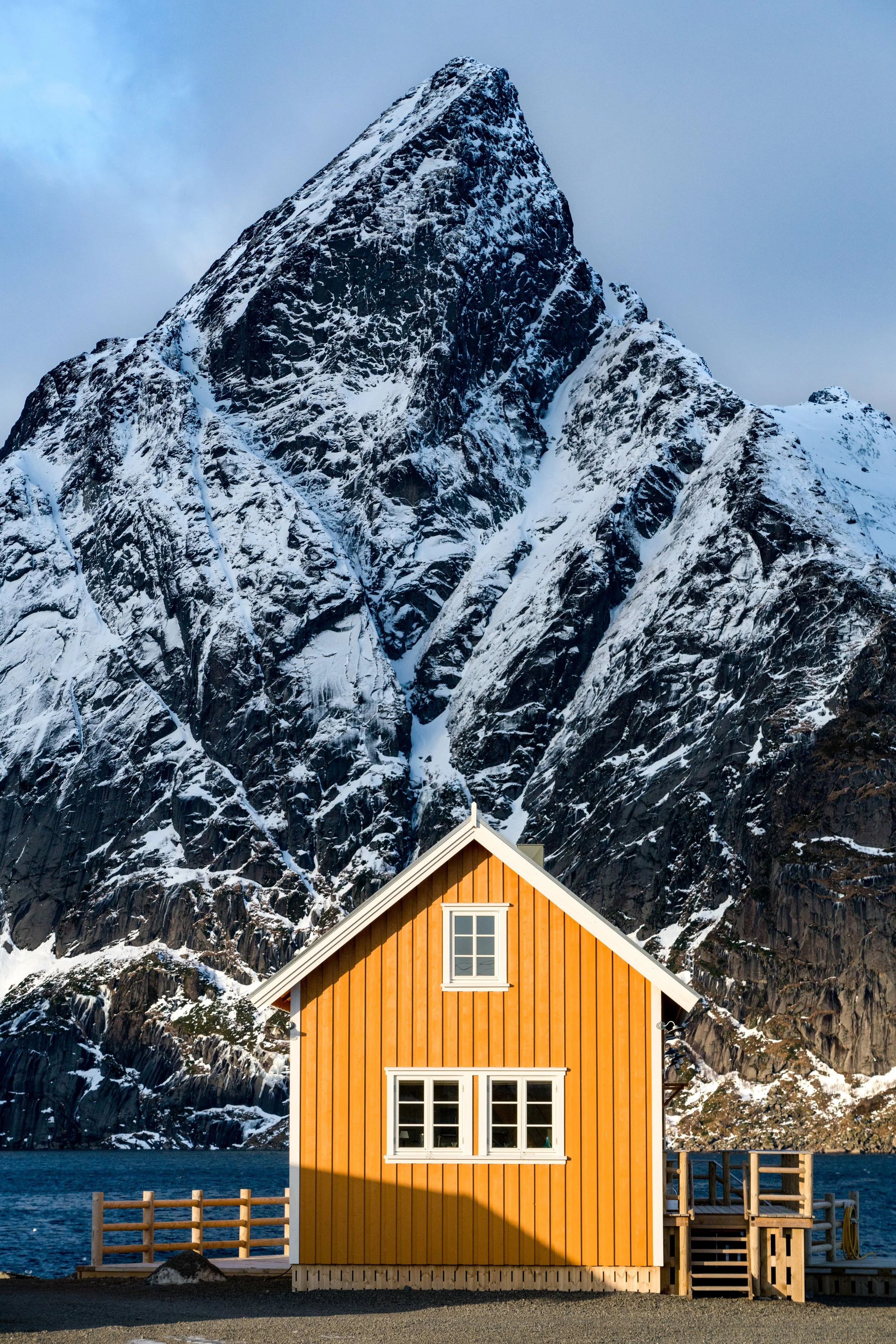 Lofoten Winter
A vibrant yellow rorbu (fishing cabin) tucked against the massive, snow-dusted granite walls of Northern Norway.