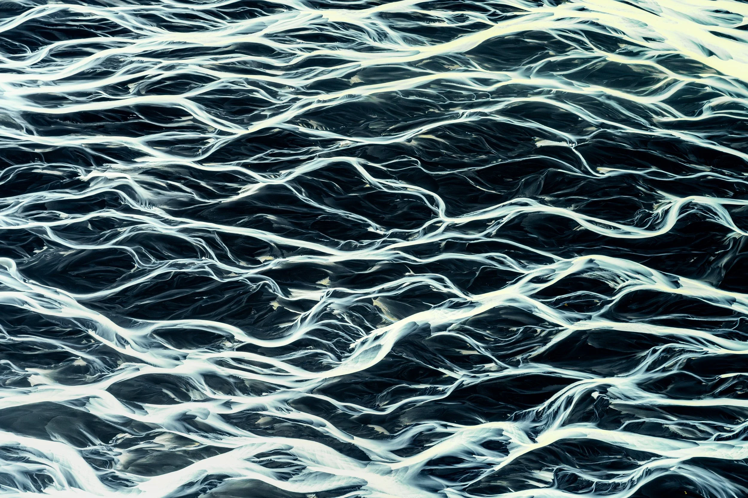 Glacial Delta
This wide-angle aerial captures the moment the river begins to fan out across the coastal plains. The complex network of shallow channels—known as a braided river—constantly shifts its path, creating a living, breathing map of the Icela