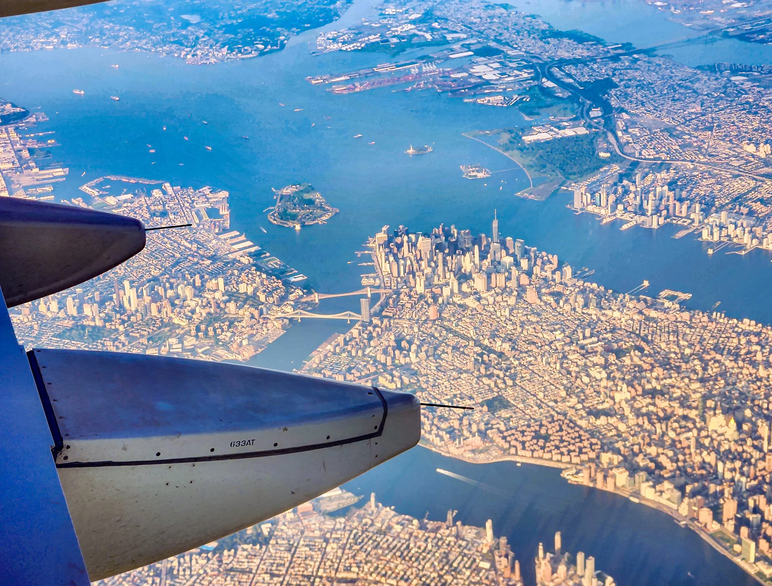The Islands of the City
Captured from a window seat during a descent, this wide-angle aerial shot reveals the iconic silhouette of the city surrounded by its waterways. The sprawling urban grid of New York is laid bare, showing the relationship betwe