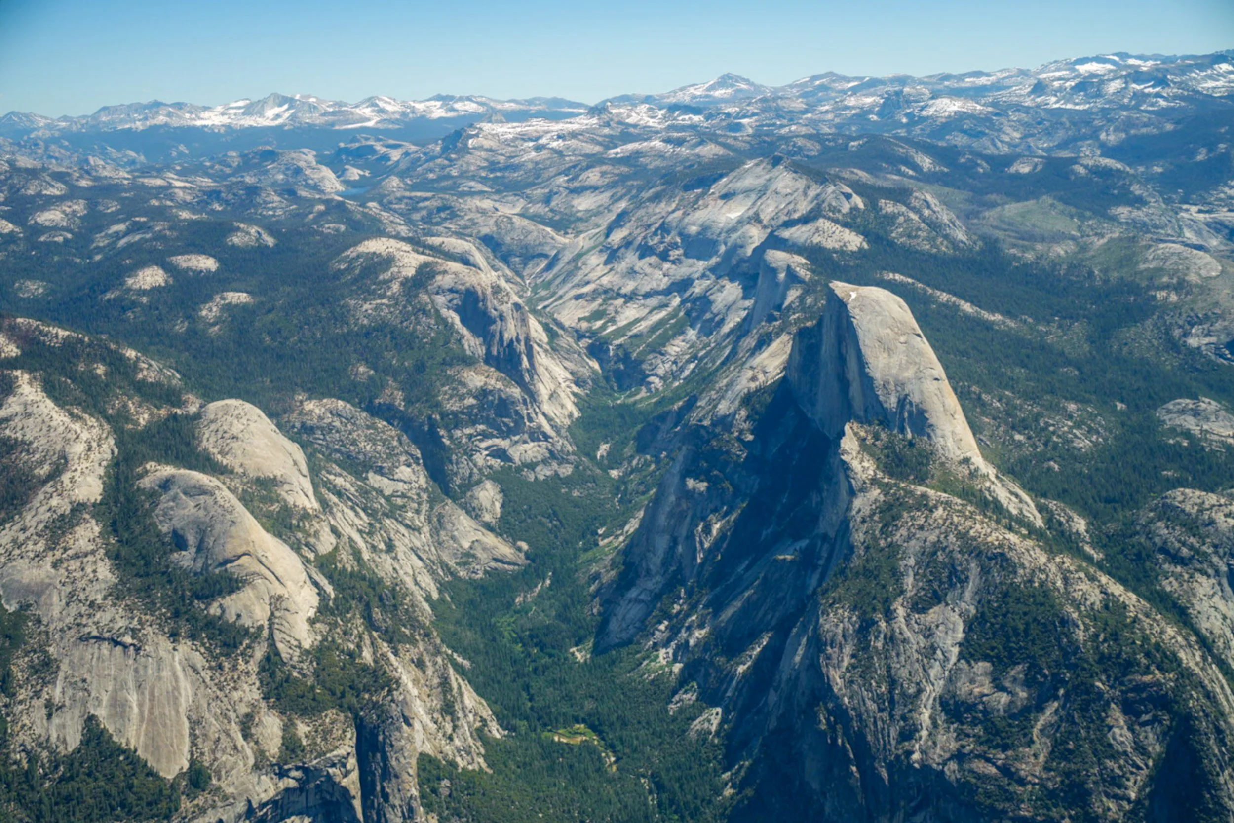 Granite Cathedral
A unique perspective of Yosemite National Park, featuring the iconic silhouette of Half Dome. From this height, the sheer scale of the glacial carving is revealed, showing the deep U-shaped valley floor and the massive granite monol