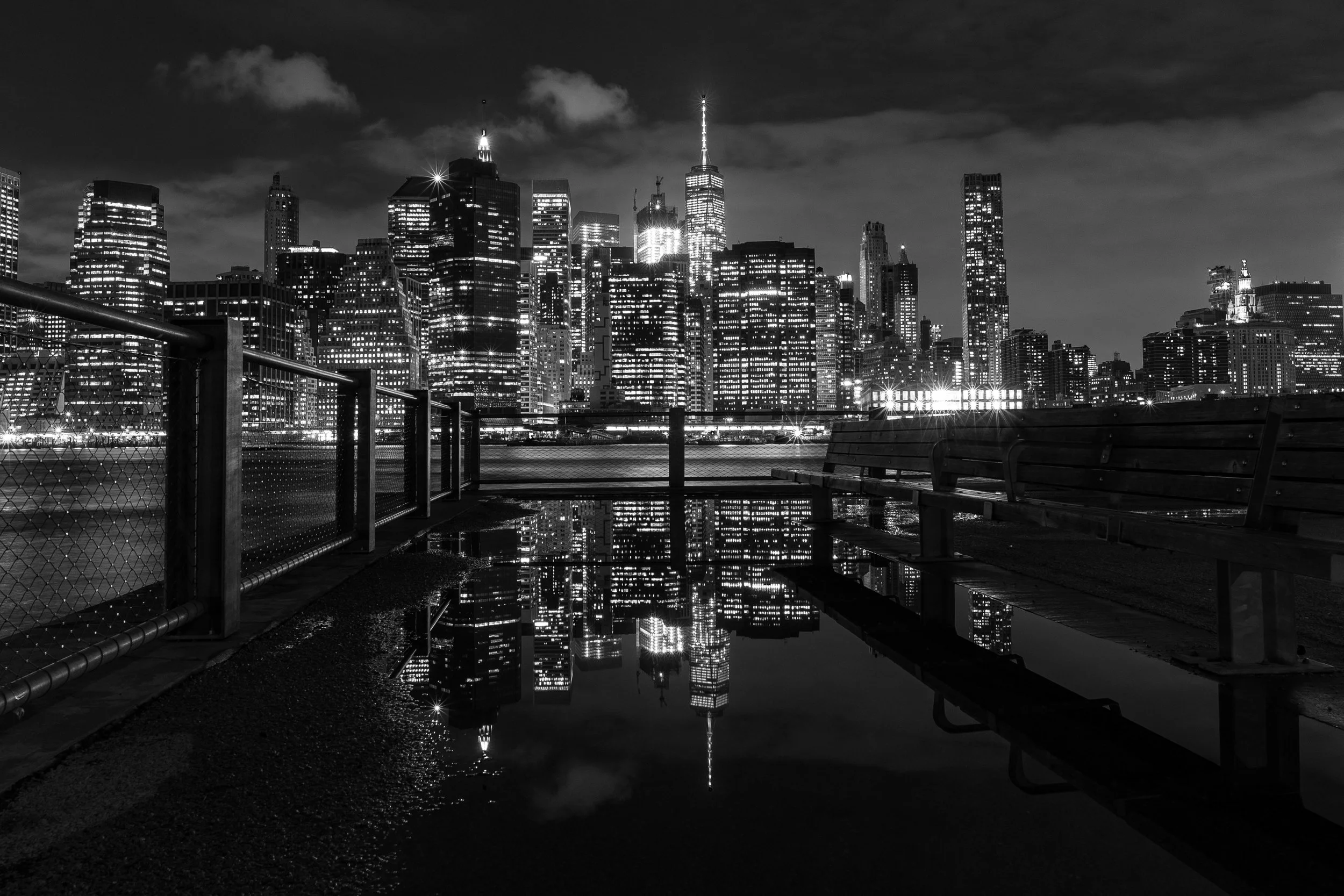 Gotham Noir
A high-contrast, black-and-white study of Lower Manhattan reflected in the puddles of a rainy evening. The monochromatic edit emphasizes the geometric patterns of the skyscrapers and the shimmering city lights. By stripping away color, th