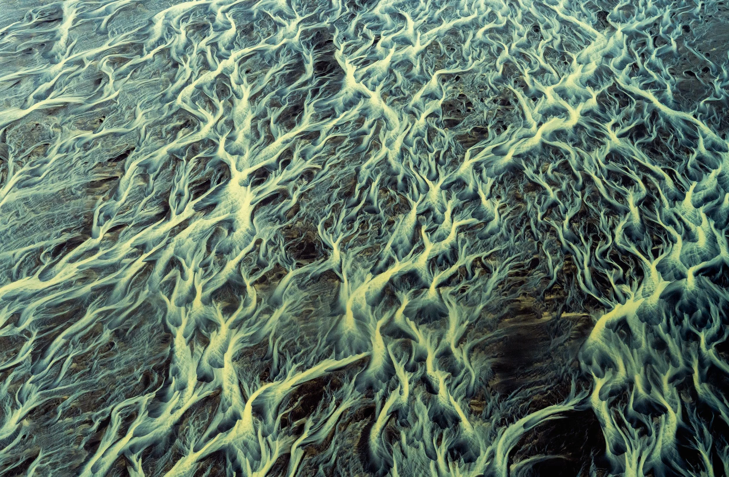 Basaltic Flow
Focusing on the dark, crusted edges of the riverbank, this photo shows the raw power of the water as it cuts through ancient volcanic deposits. The contrast between the rigid, dark land and the fluid, bright water creates a powerful sen