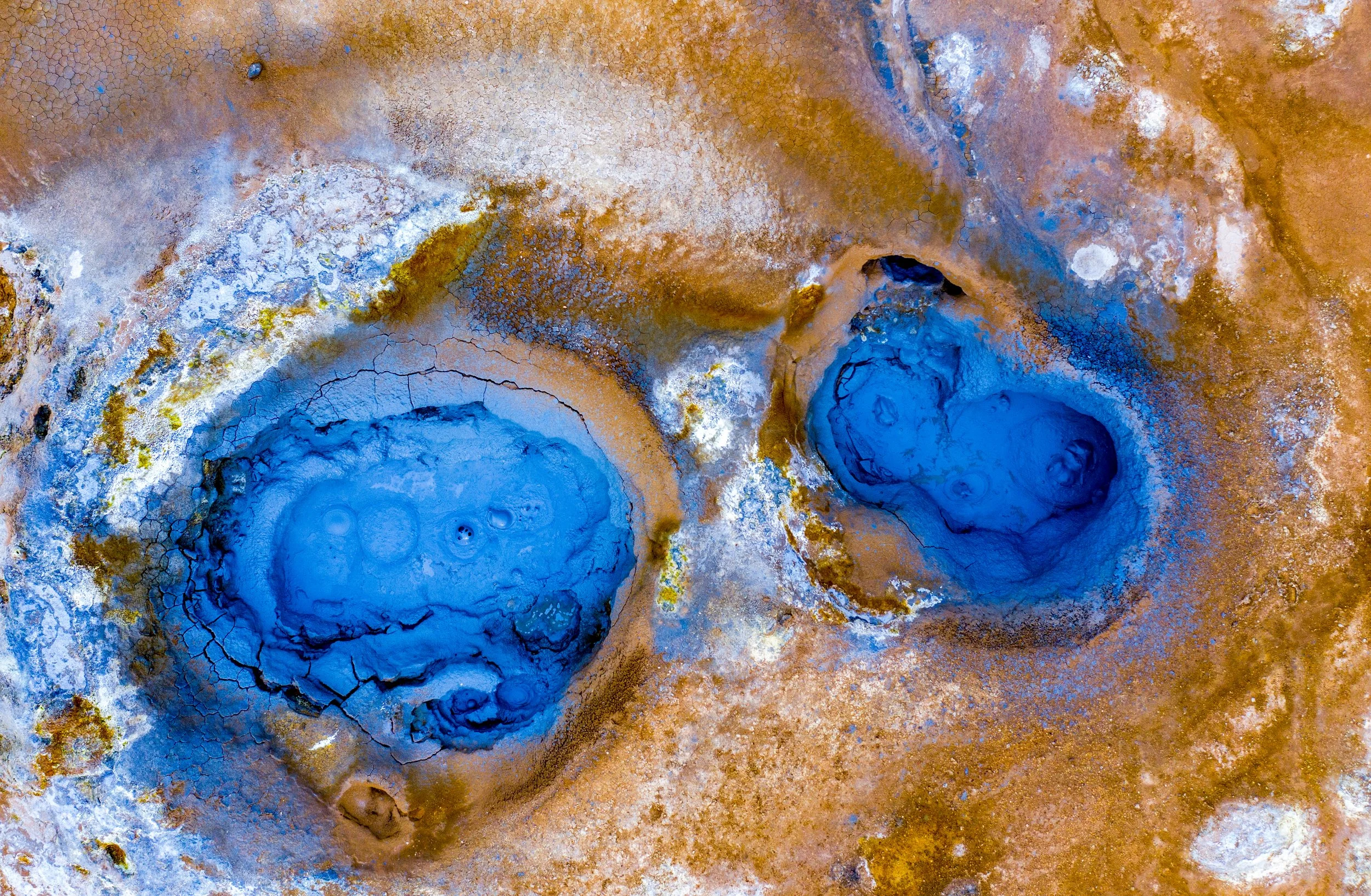 Cerulean Vents of Hverir
Located at the foot of the Námaskarð pass, these bubbling mud pools and geothermal vents showcase the intense mineral activity of the Mývatn region. The striking blue color is a result of silica and sulfur suspended in the bo