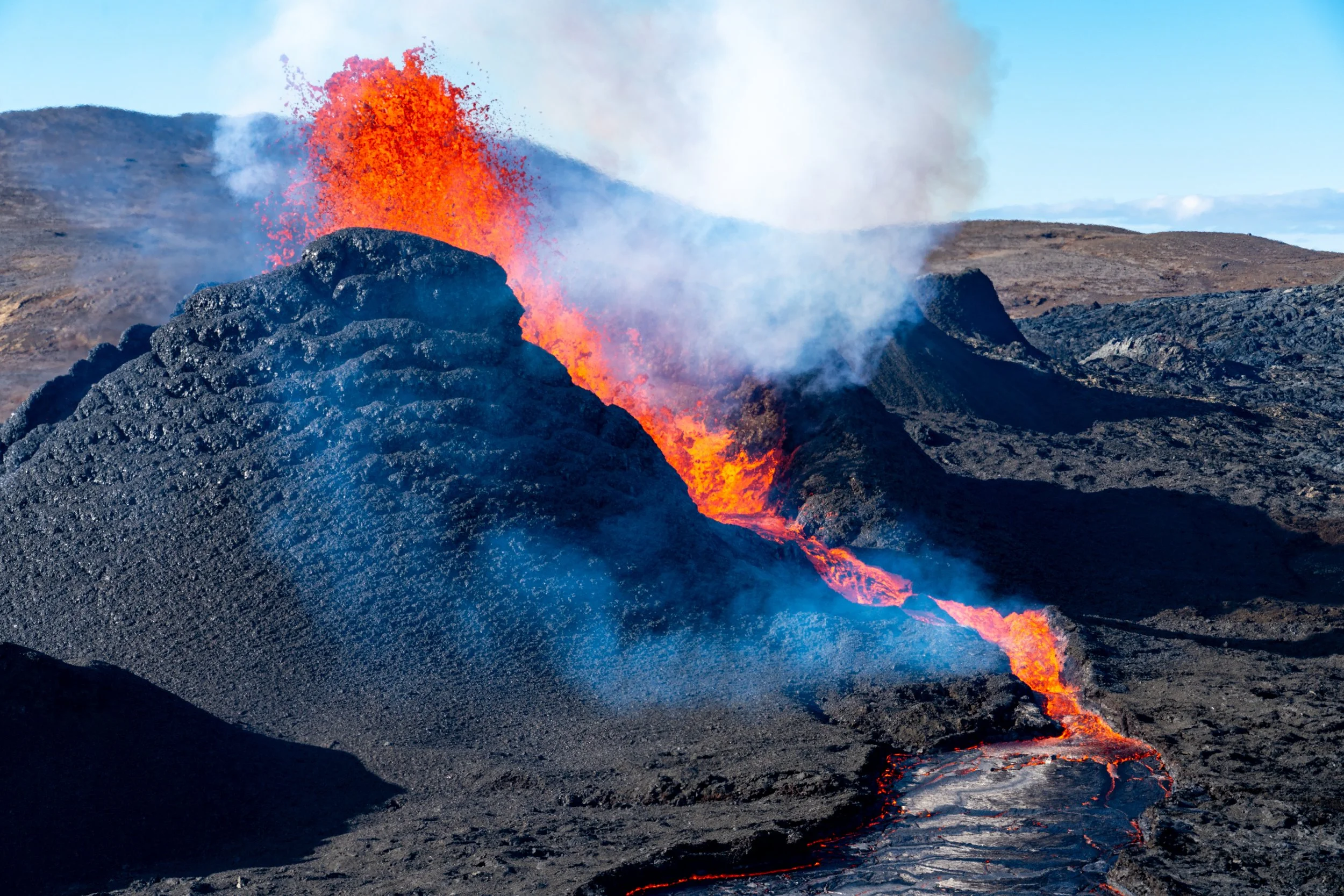 Cascading Fire
As the pressure within the main crater builds, molten basalt breaches the rim, creating a series of fire-falls that feed the growing lava field below. This shot captures the fluid, almost liquid-like nature of the lava as it navigates 