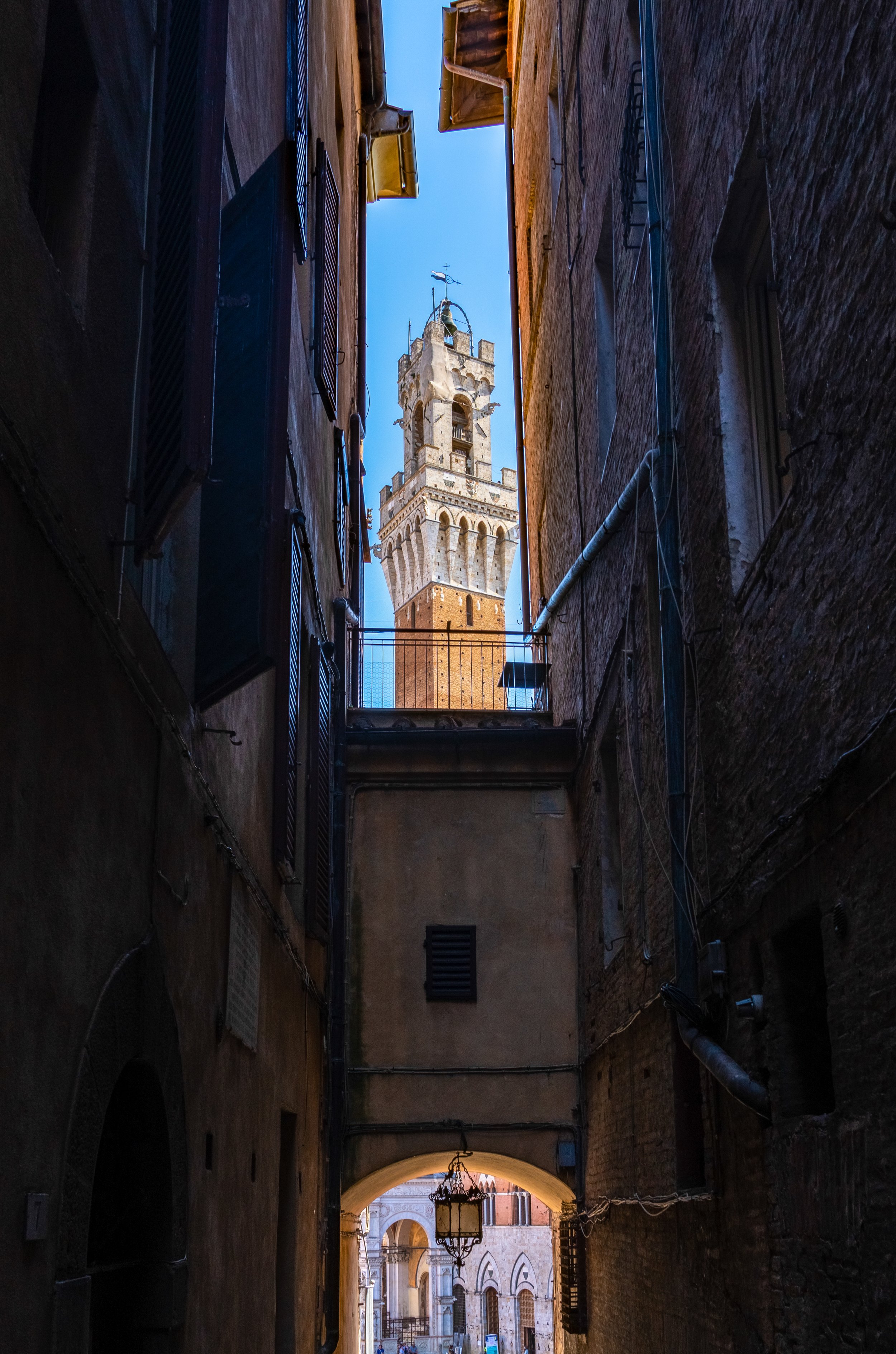 Siena
Framed by the shadows of a narrow medieval alleyway, the 14th century Torre del Mangia rises into the sky. The shot emphasizes the soaring height of what was once the tallest structure in Italy. 
