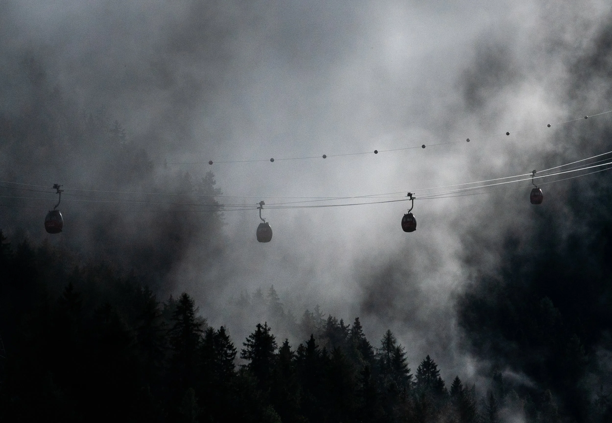 Alpine Transit 
A solitary gondola suspended in the morning silence above a thick blanket of valley fog.