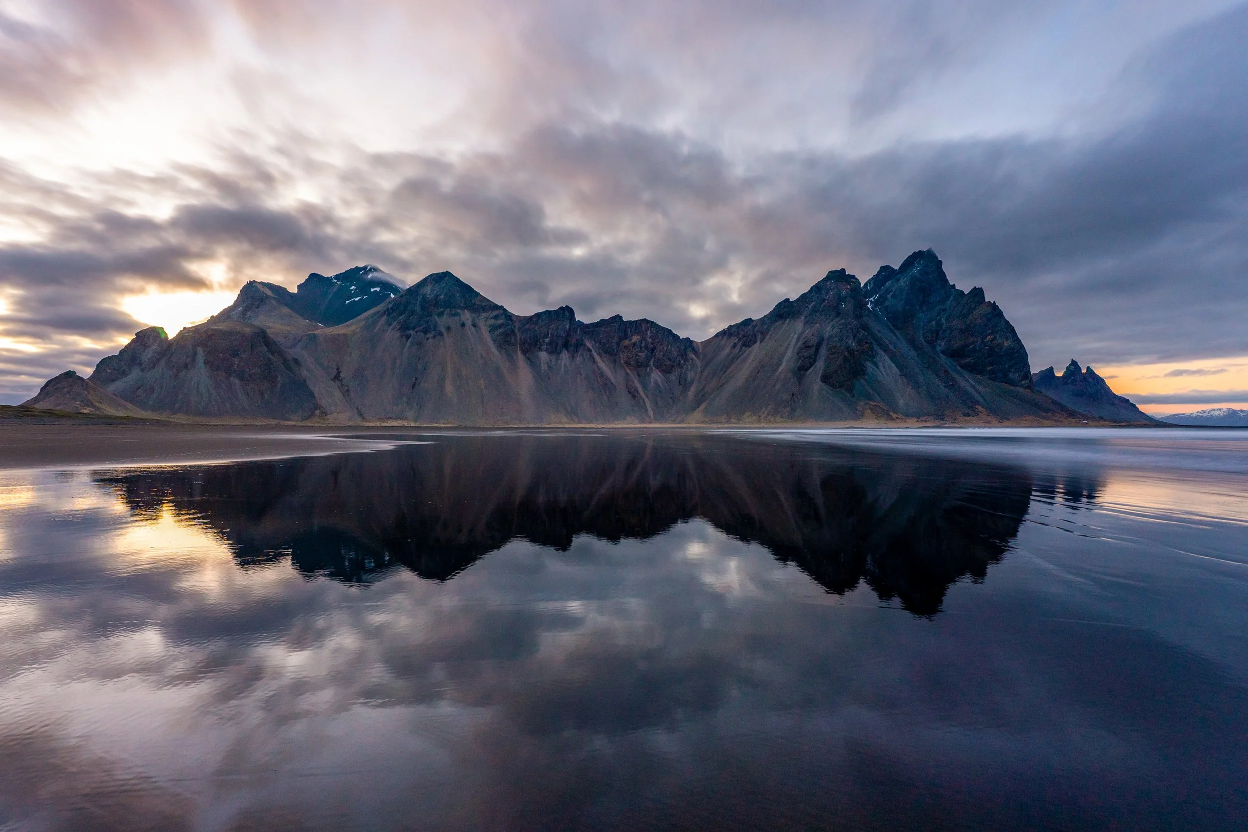 Vestrahorn 
Where the black sand dunes meet the "Batman Mountain." The moody, dark slopes of Vestrahorn reflecting in the tidal lagoons create a surreal, cinematic atmosphere.