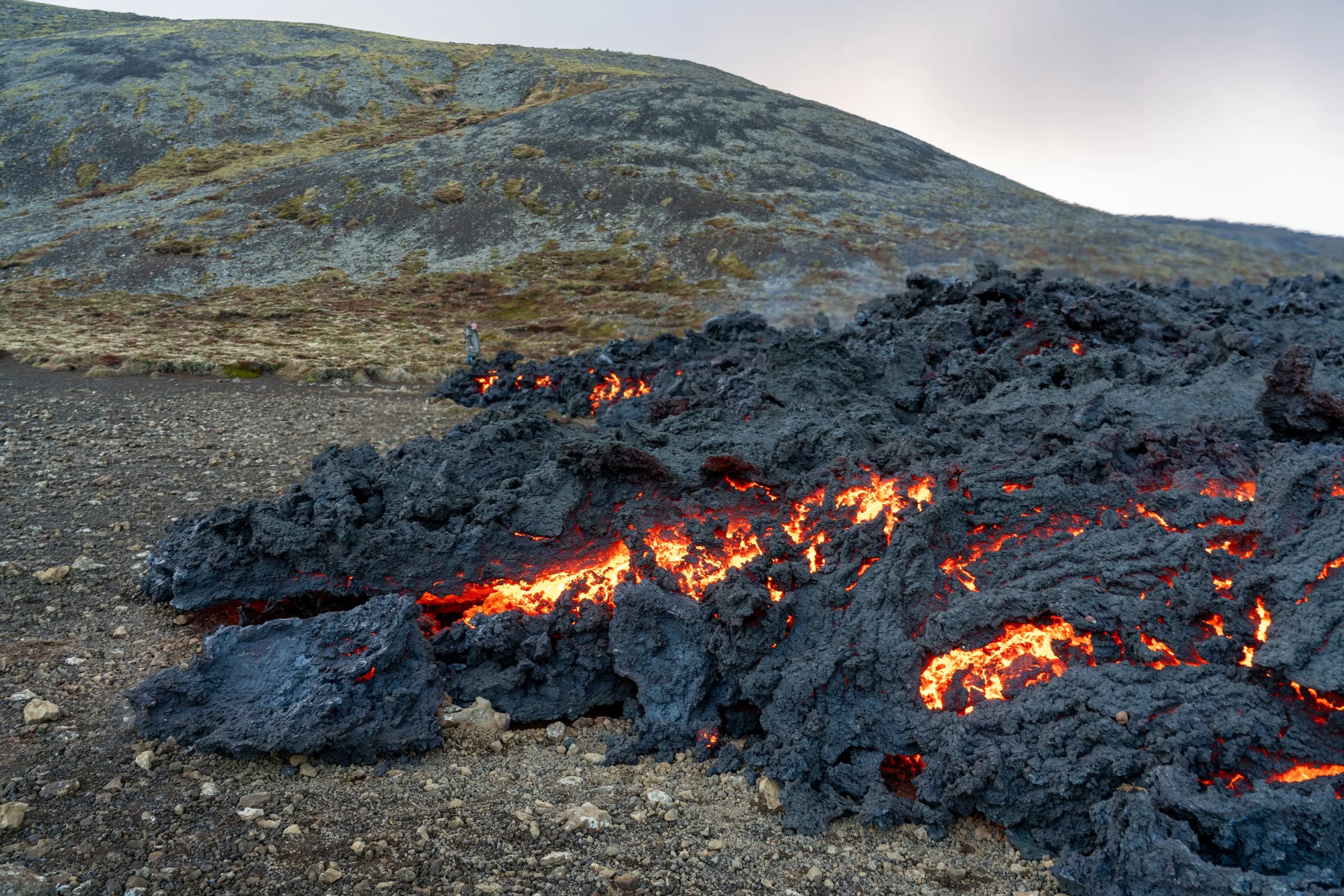 The Slow Advance

Description: A close-up study of a cooling basalt flow as it moves across the Icelandic highlands. The silvery-black crust of the lava frequently cracks to reveal the glowing, 1,200°C interior pushing it forward from within. This im
