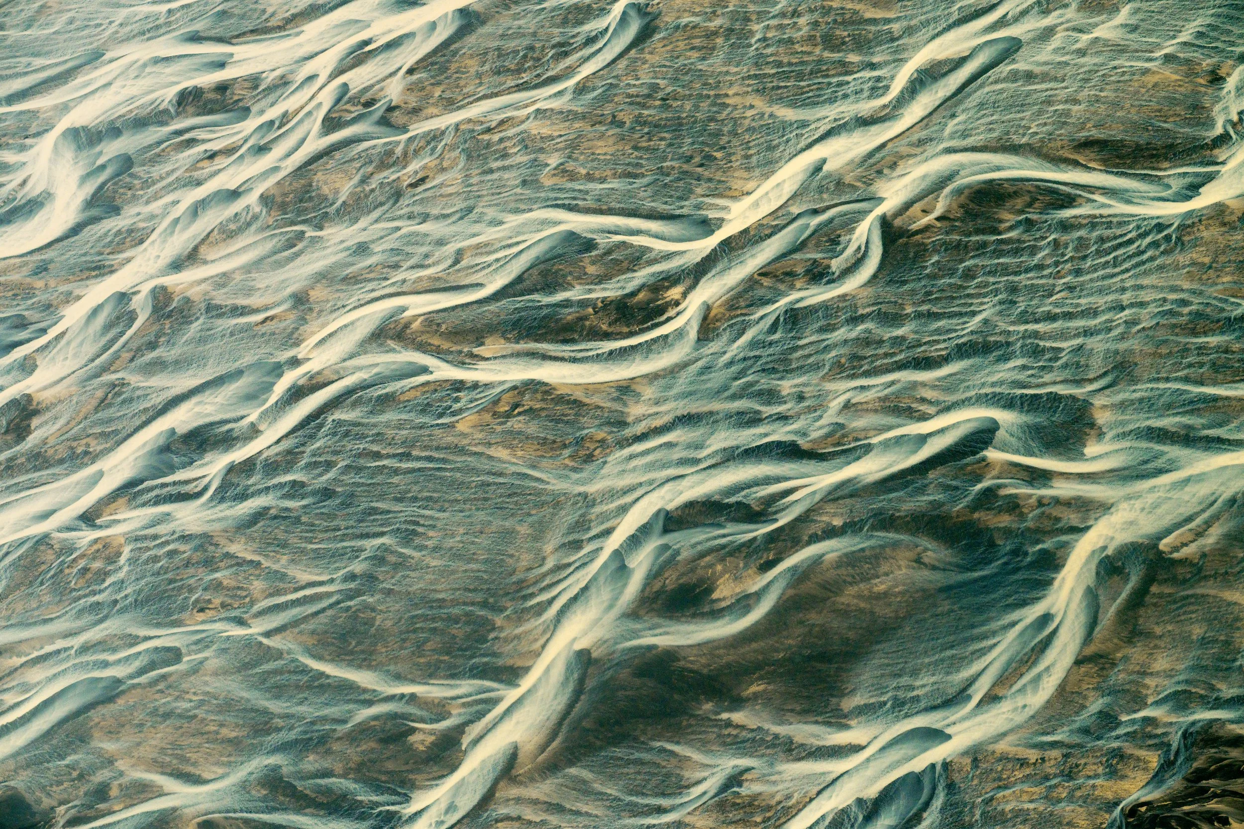 Azure Threads
A rare shot capturing a deeper, clearer channel within the river system. While most of the water is clouded with silt, this deep blue "thread" indicates a swifter current or a different source of meltwater, adding a pop of vibrant color