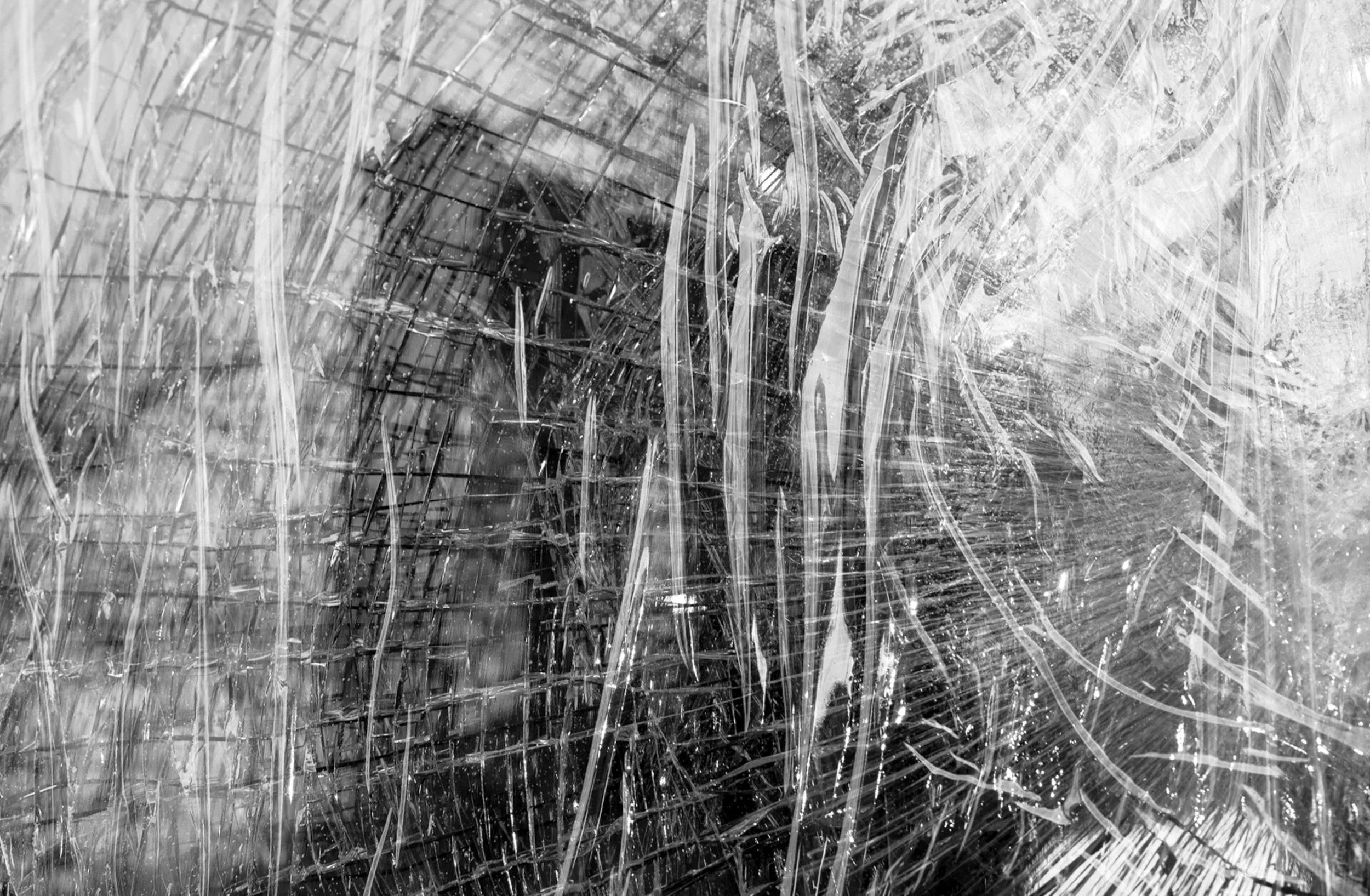 Shards of Gotham
A striking, abstract perspective of the Brooklyn Bridge seen through the crystalline patterns of shattered glass. This black and white composition fragments the iconic suspension cables and gothic arches into a web of sharp lines and