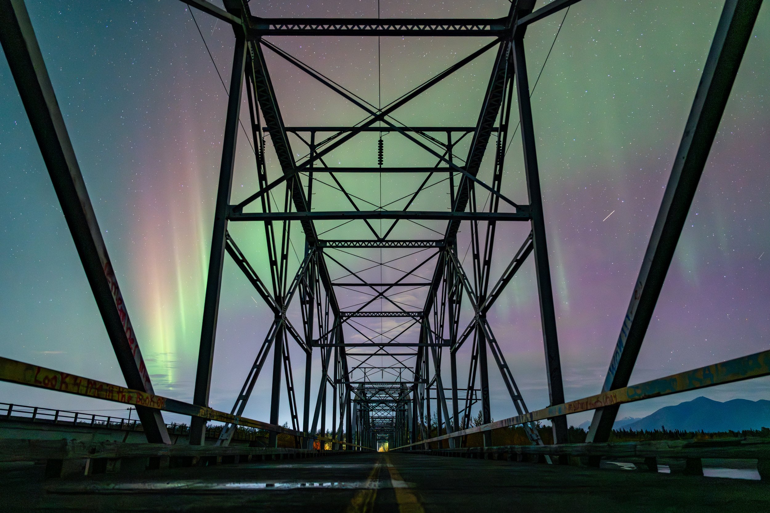 Knik River Bridge
The vibrant green ribbons of the Aurora Borealis dance above the historic steel trusses of the Knik River Bridge near Palmer, Alaska. This long exposure captures the ethereal movement of the solar particles hitting the atmosphere, f