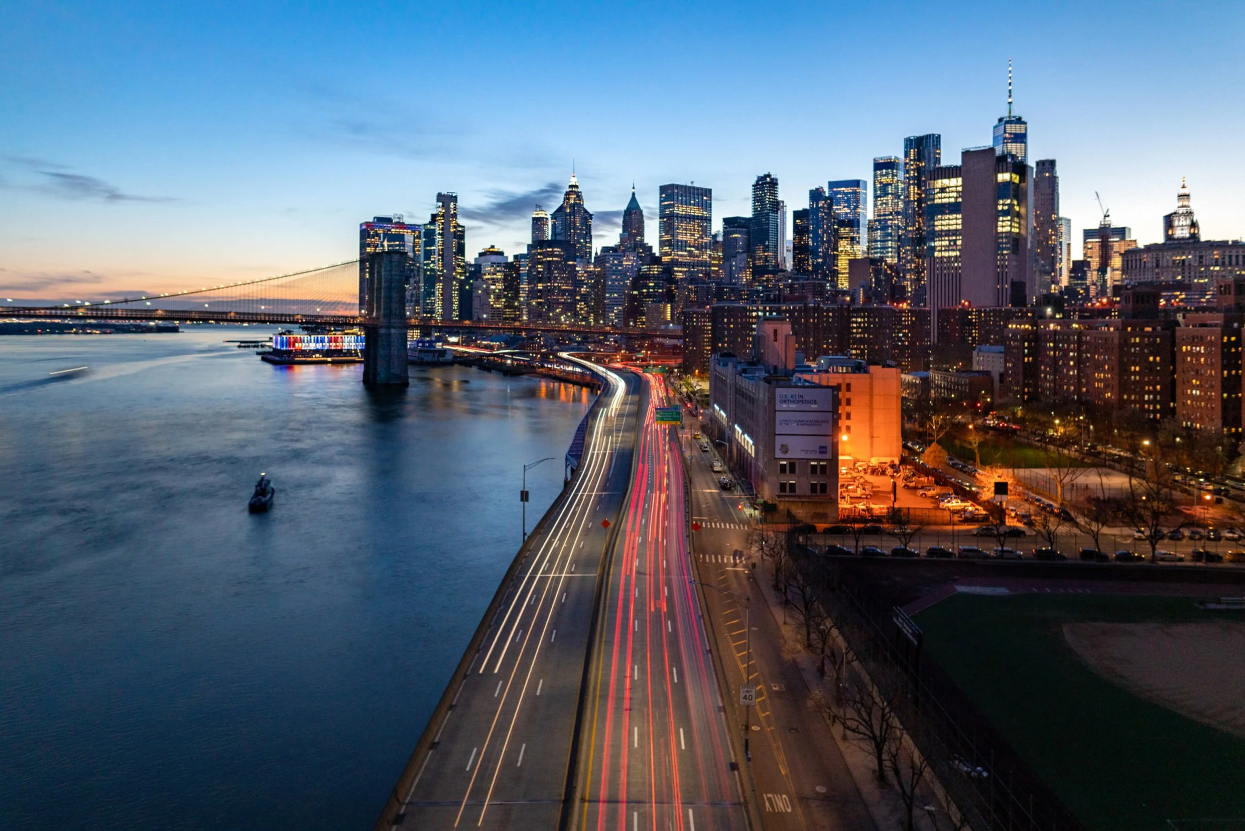 Electric Arteries
Looking down from the Manhattan Bridge at the sweeping curves of the FDR Drive. The motion blur of the cars creates a river of gold and red light that snakes along the East River waterfront. This high-angle perspective highlights th