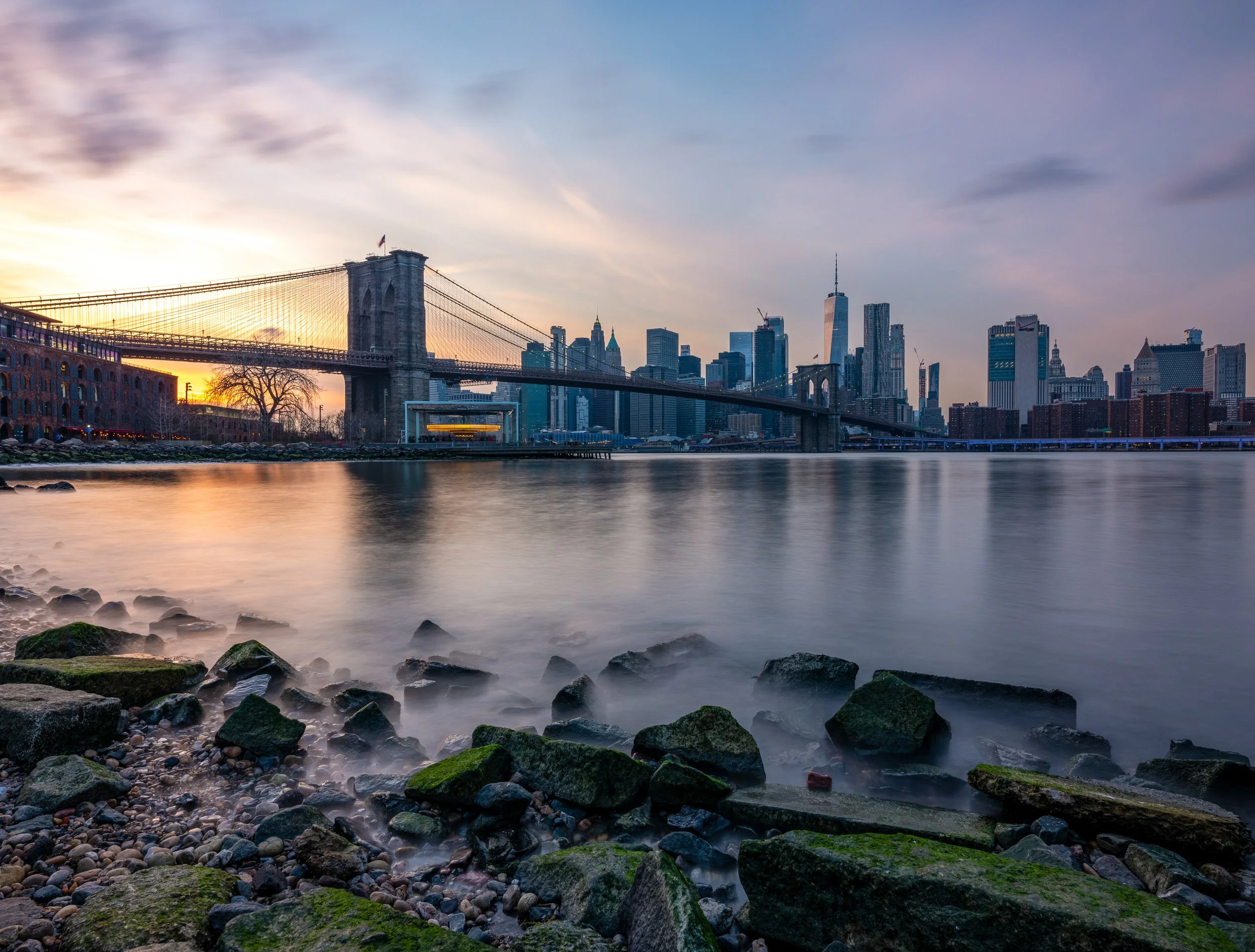 Pebble Beach
Captured  in Brooklyn Bridge Park, this shot offers a balanced view of the East River and the Manhattan skyline. The natural textures of the rocks in the foreground provide a grounded contrast to the glass towers of the Financial Distric