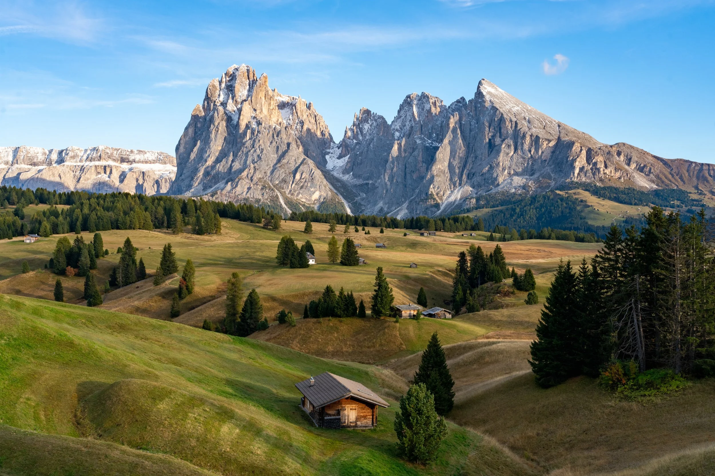 Alpine Dwelling
A detailed view of a traditional mountain village nestled in the lush, green slopes of the Dolomites. The shot highlights the classic wooden and stone architecture of the region, surrounded by dense pine forests and steep, mist-covere