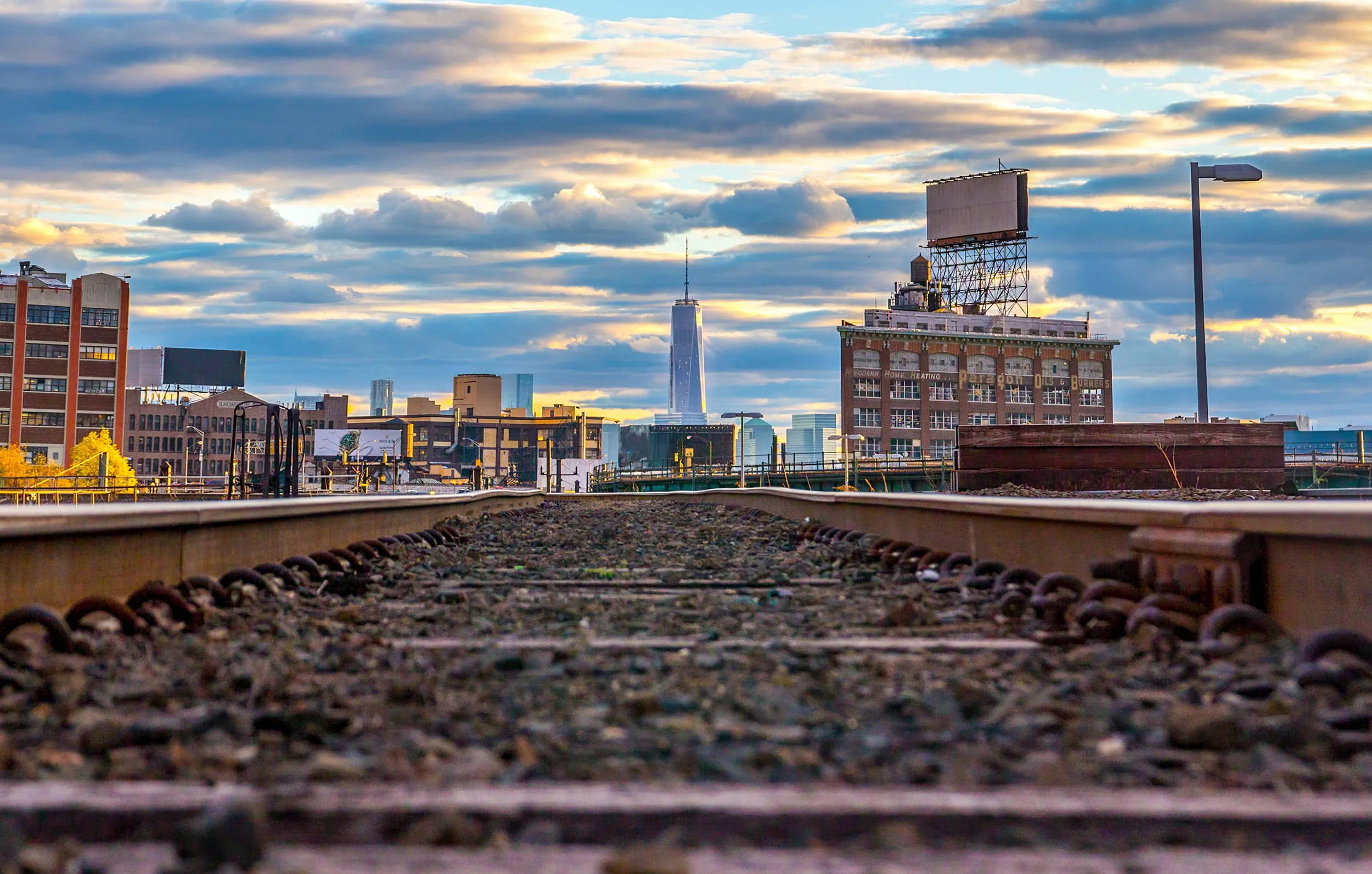 The Iron Path
Looking down a set of weathered train tracks toward the gleaming glass of the One World Trade Center. This composition uses the parallel lines of the rails as a lead-in, contrasting the gritty, industrial history of the region with the 