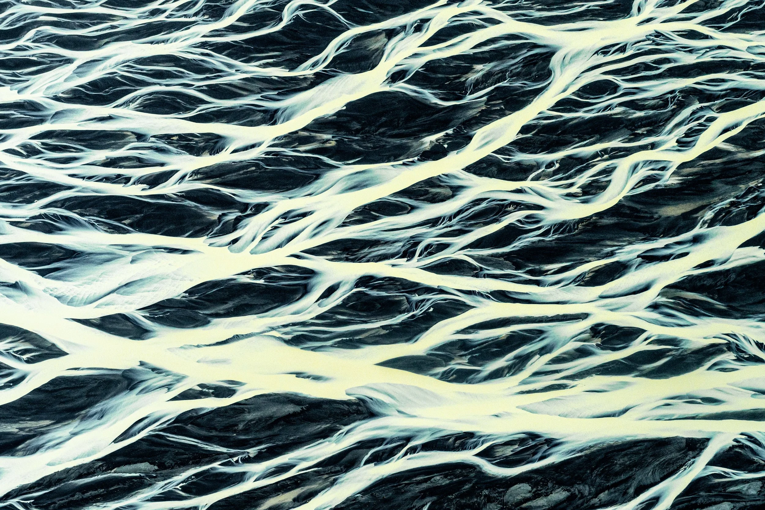 Sediment Swirl
In this frame, the glacial silt creates marble-like swirls within the larger flow. These patterns are caused by the interaction between the heavy volcanic minerals on the river bottom and the lighter glacial milk above, turning the lan