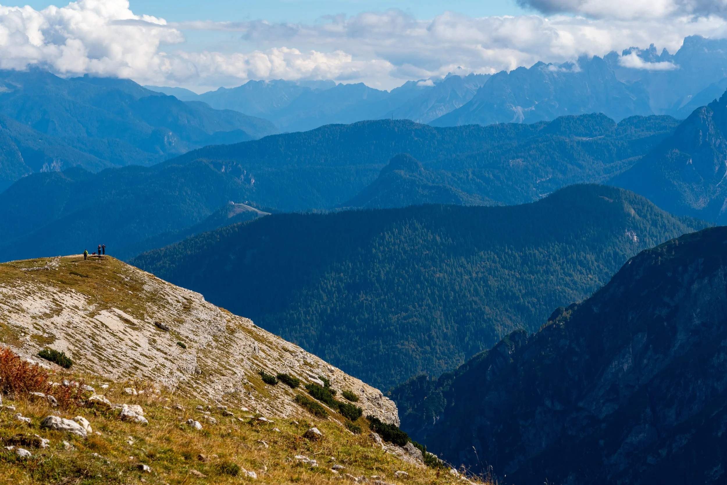 Dolomite Vista
A vast, sweeping view from a high-altitude ridge in the Dolomites. The shot captures the receding layers of mountain peaks as they fade into the hazy distance, emphasizing the immense scale and silent majesty of the Italian Alps. The g