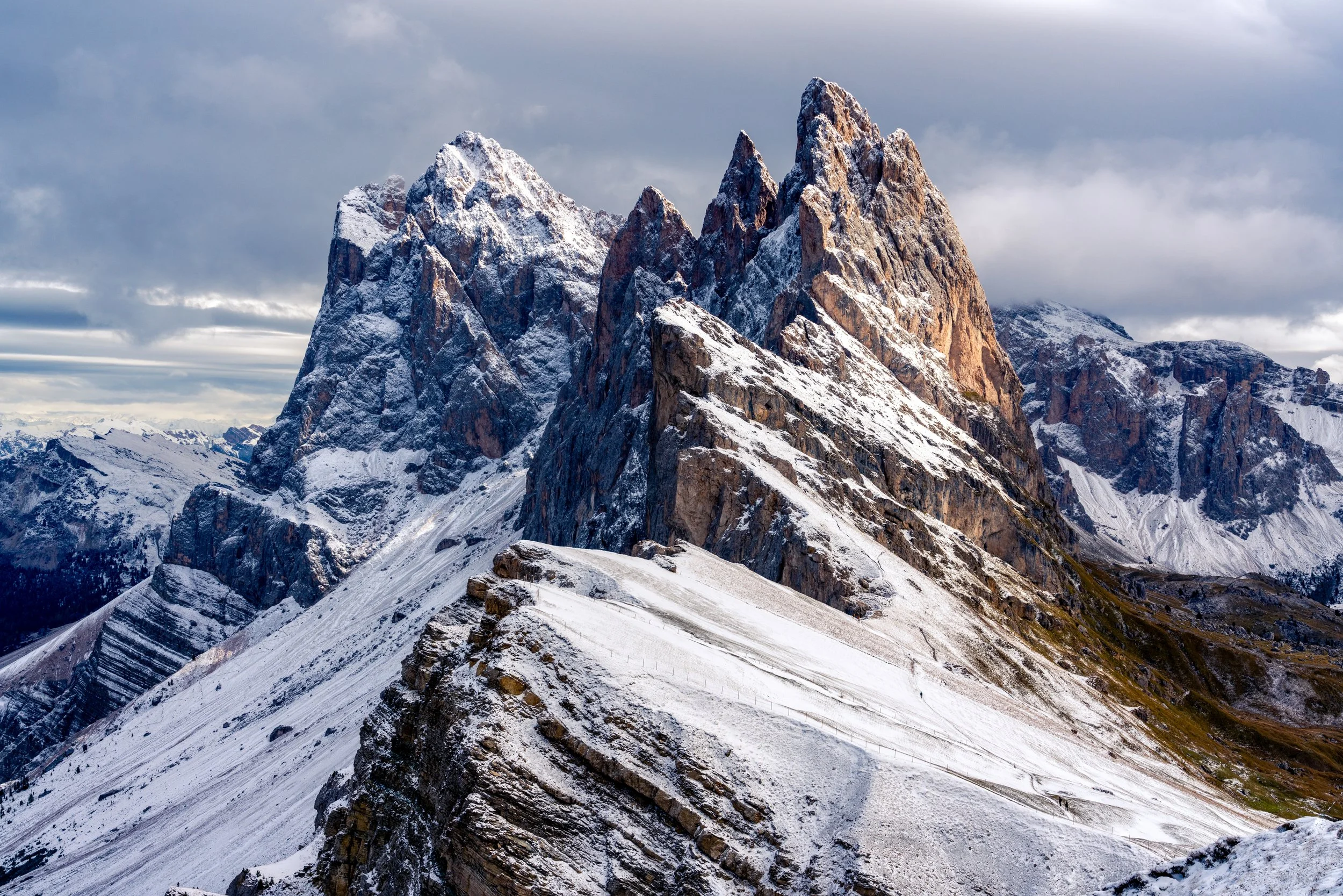 The Edge of the Odle
A view of the Seceda ridgeline in the Puez-Odle Nature Park. This shot captures the dramatic collision of grassy alpine meadows and the jagged, vertical spires of the Odle (Geisler) group. The slant of the mountain face provides 