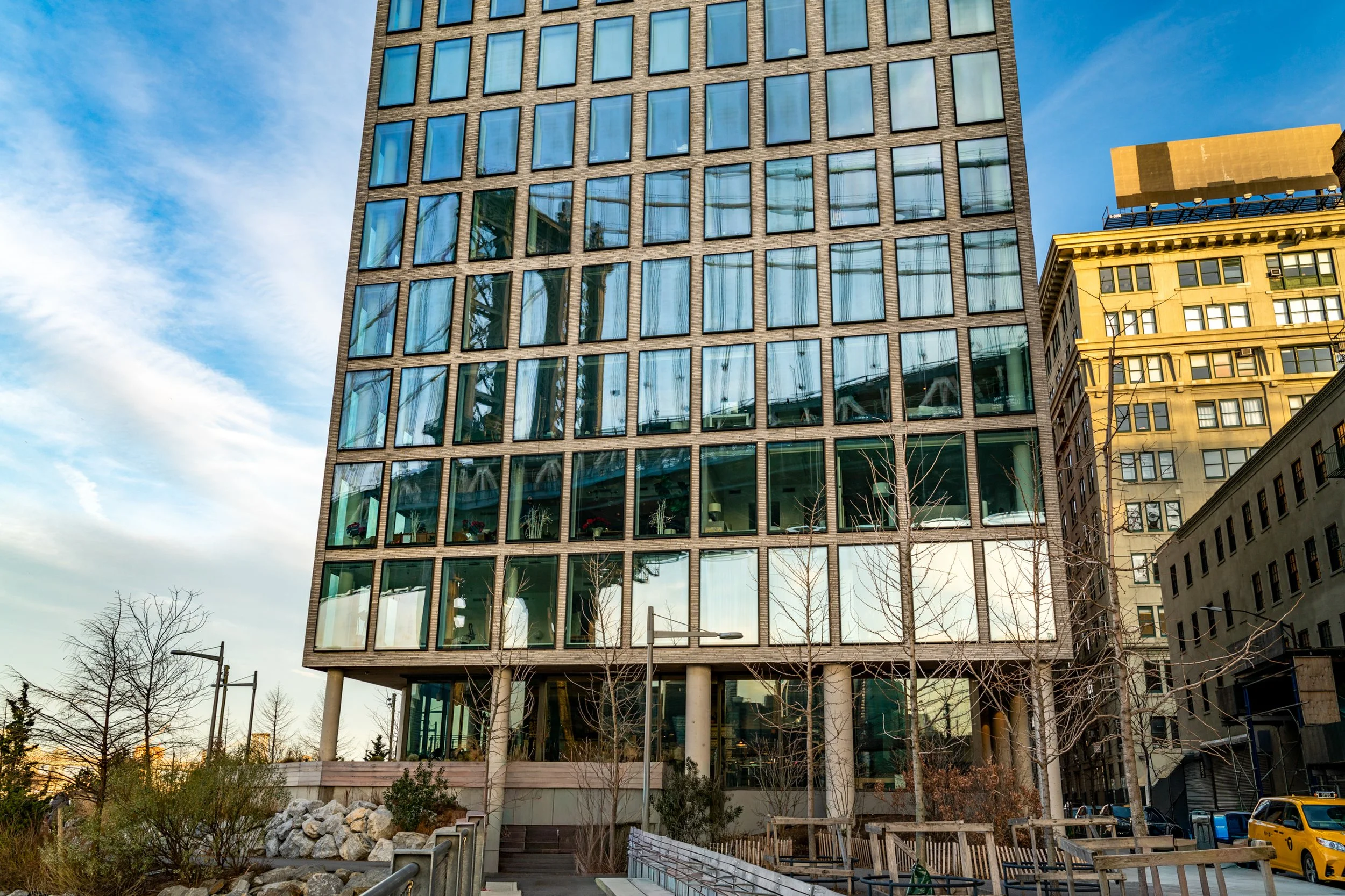 Urban Mirror
A striking architectural reflection of the Manhattan Bridge captured on the glass exterior of a contemporary building in DUMBO. The grid-like structure of the window panes fragments the blue steel of the bridge, creating a layered compos