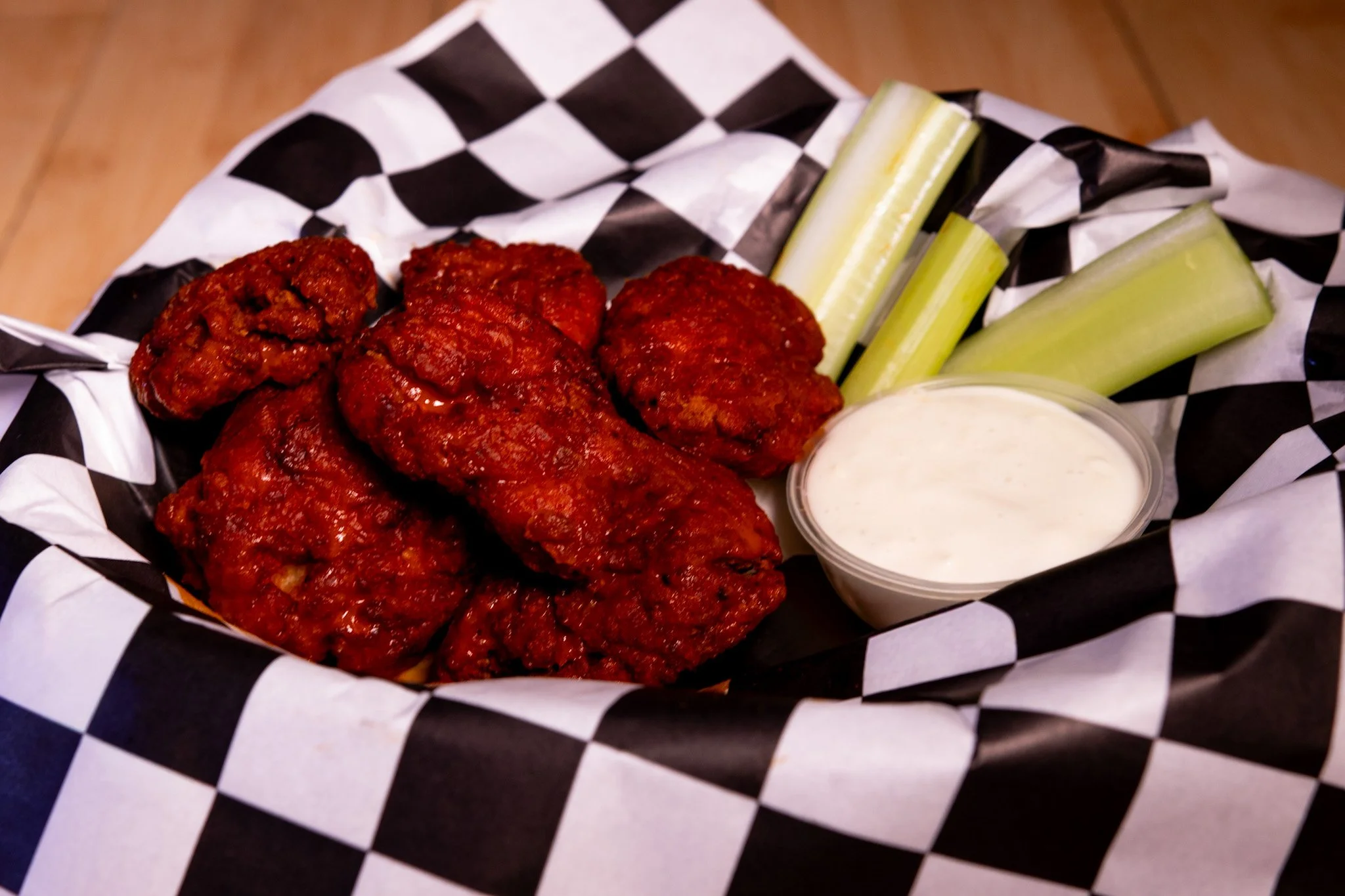Basket of fried chicken wings with celery sticks and ranch dressing
