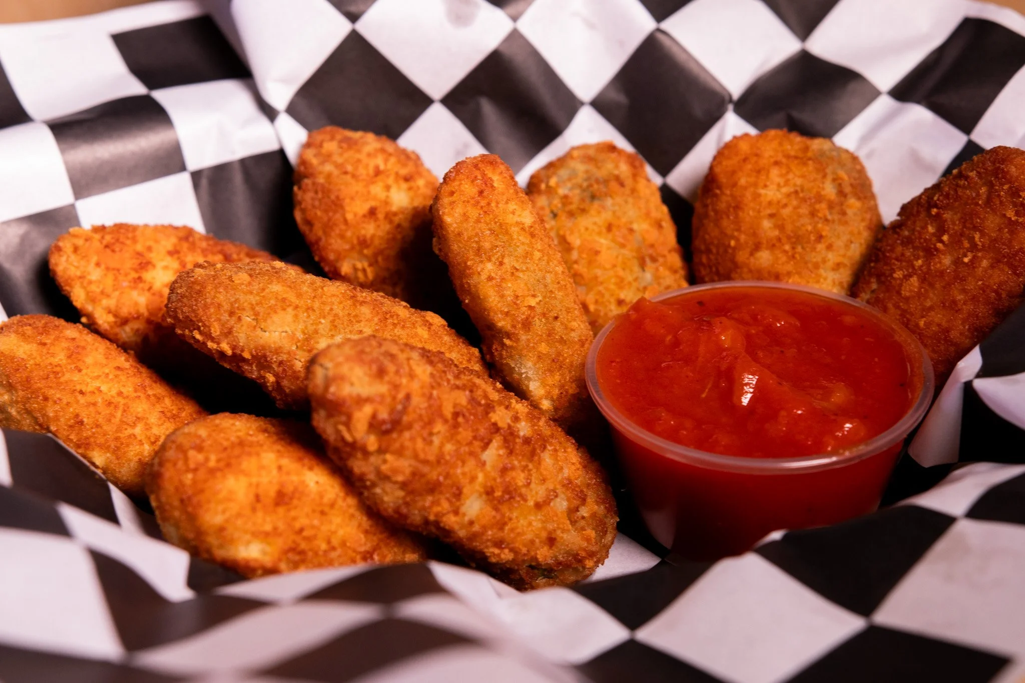 A basket of fried mozzarella sticks with marinara sauce.