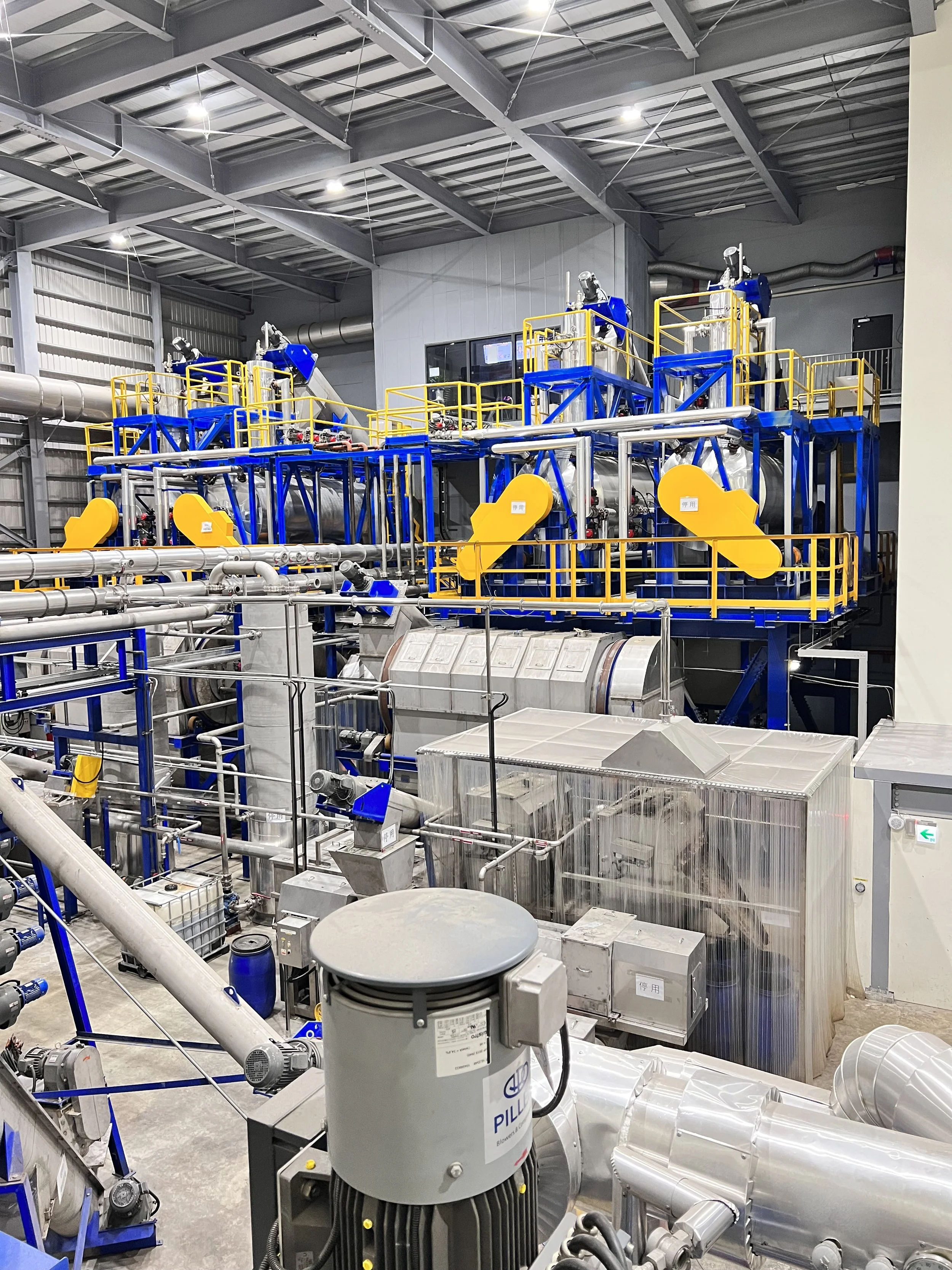 Industrial machinery with pipes, valves, and metal structures in a factory or processing plant.