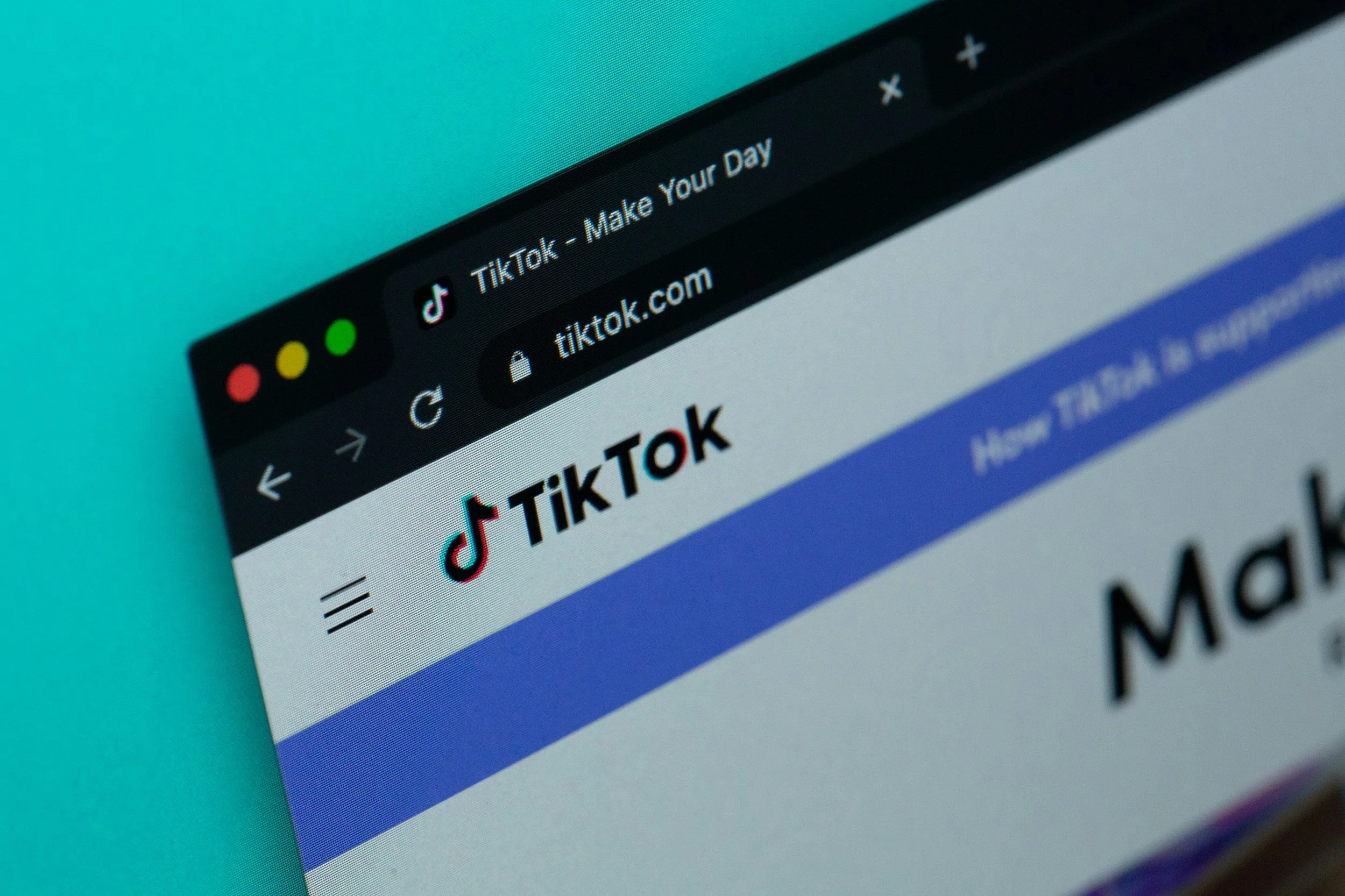 Close-up of a computer screen showing the TikTok website homepage with the logo and a partially visible headline.