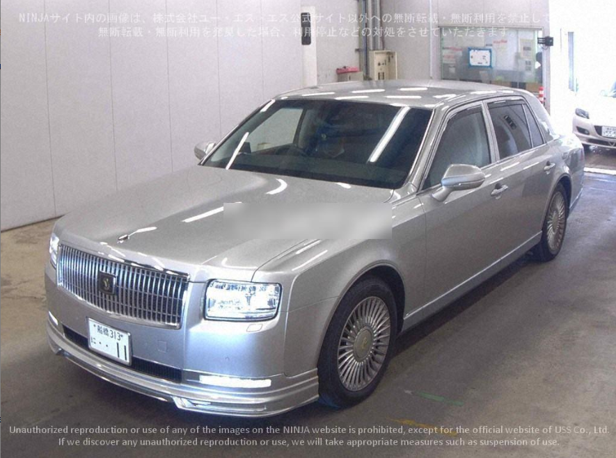 A silver luxury sedan car parked indoors, with Japanese license plate, in a well-lit garage or parking area.