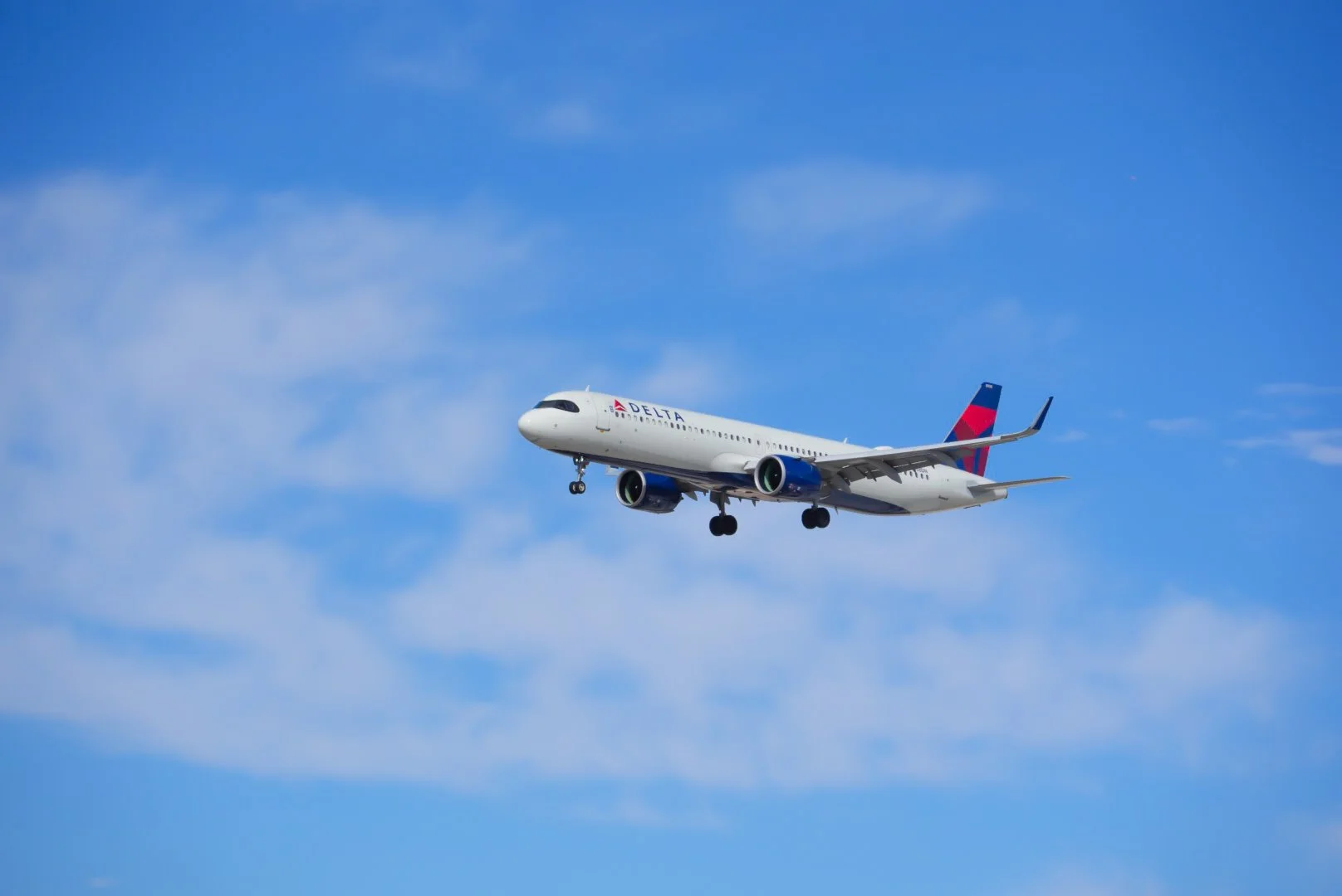 A Delta airplanes flying in the sky with some clouds.