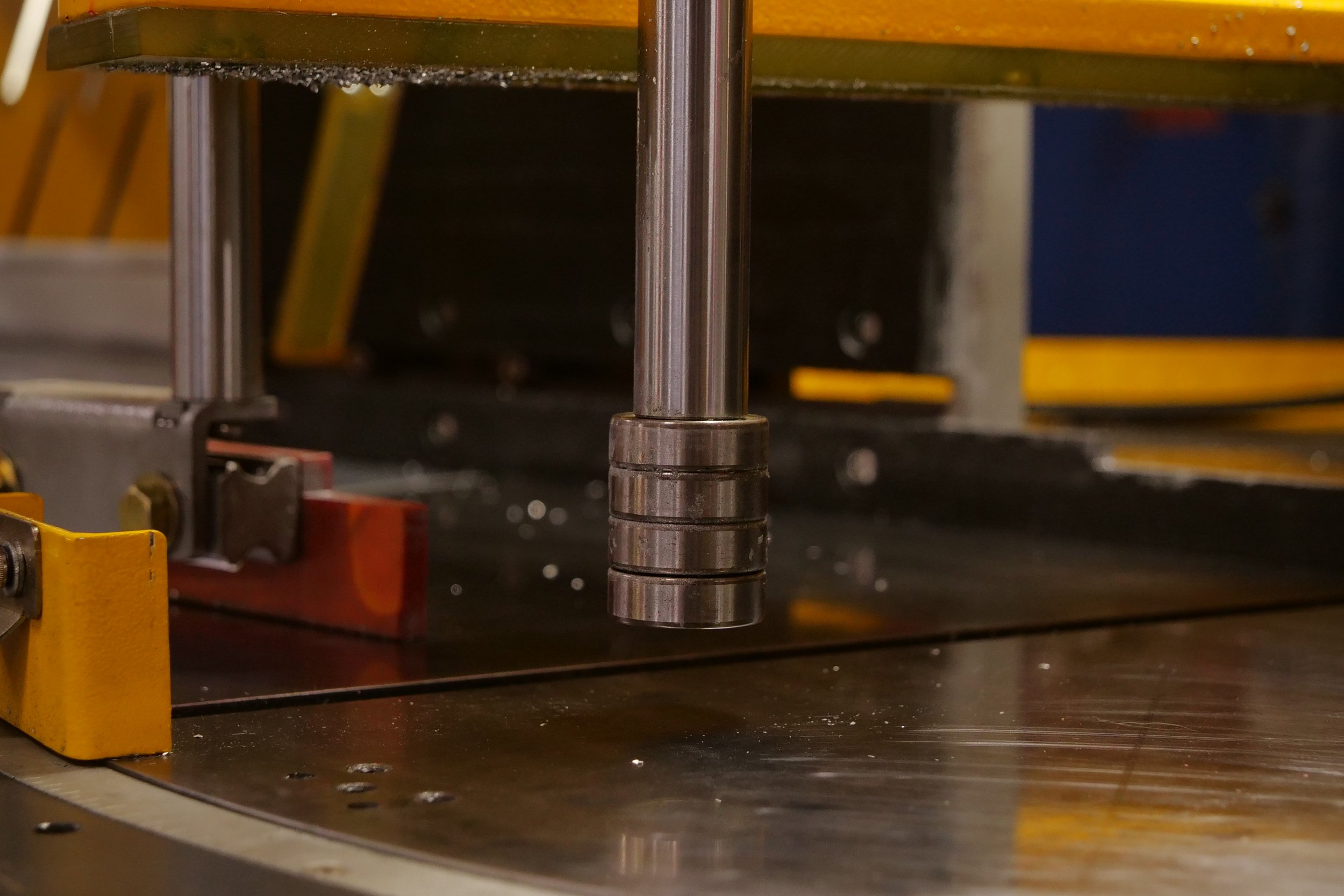 Close-up of a mechanical metal shaft on a yellow and black industrial machine or equipment.