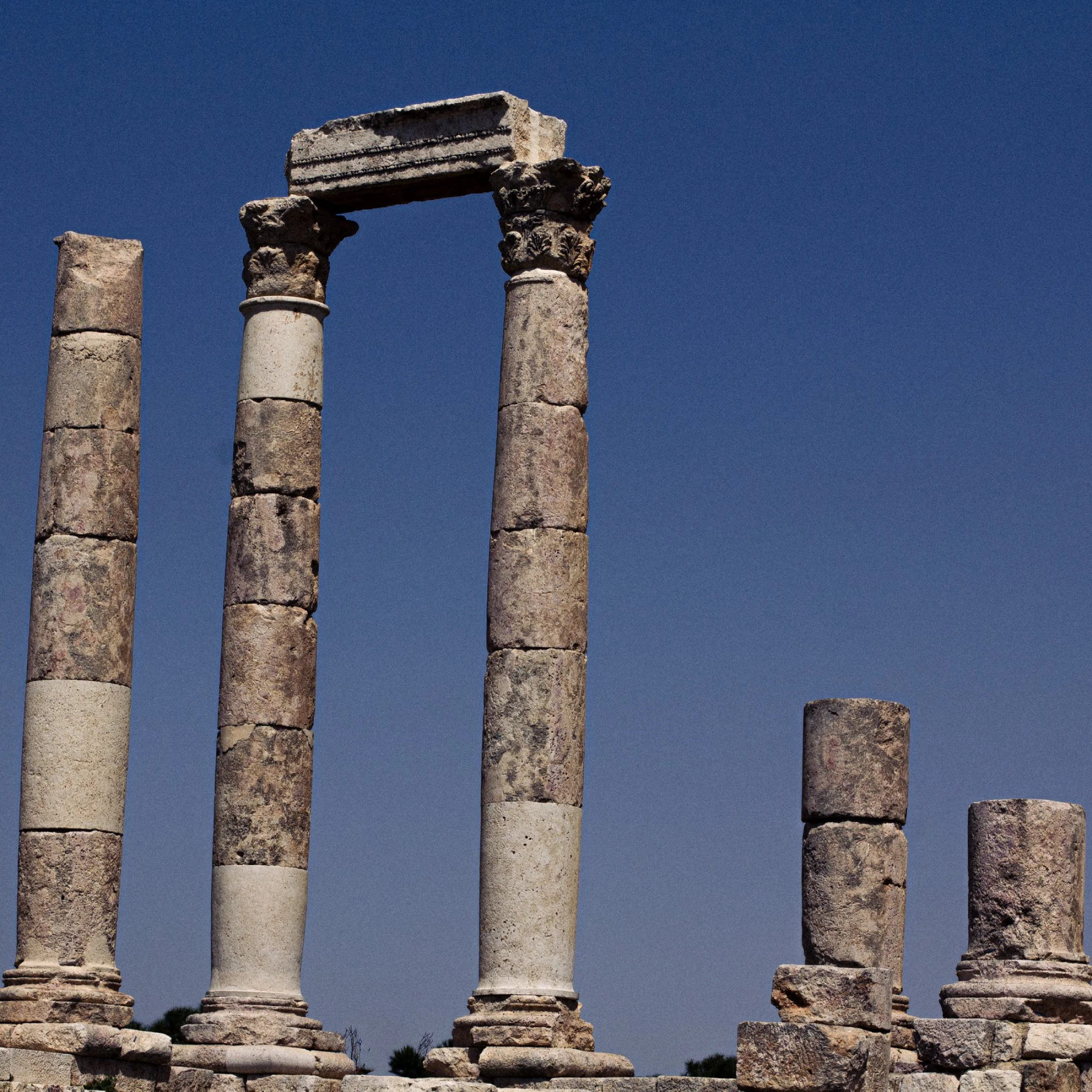 Ancient stone ruins with columns and a clear blue sky in the background.