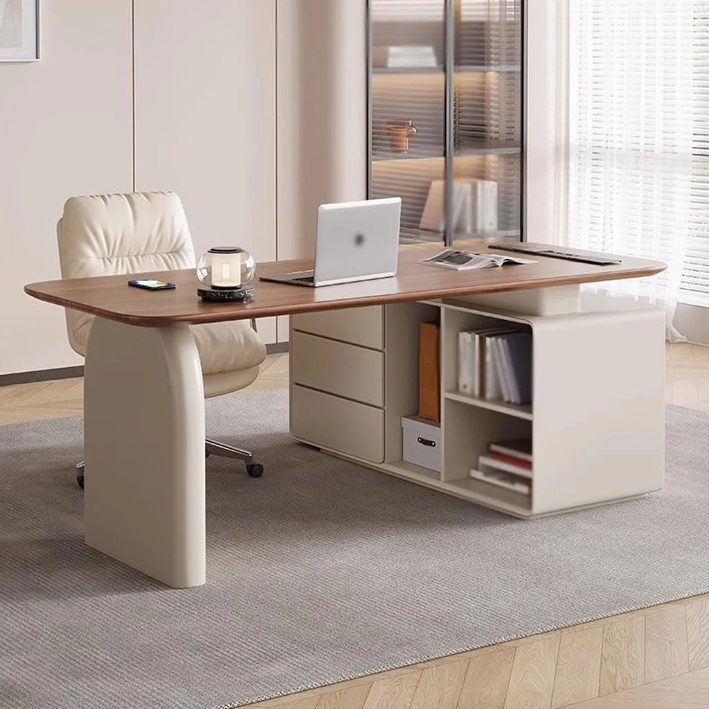 Modern office with a wooden desk, white chair, open laptop, candle, remote, open magazine, books and file on bookshelves, and sunlight through blinds.