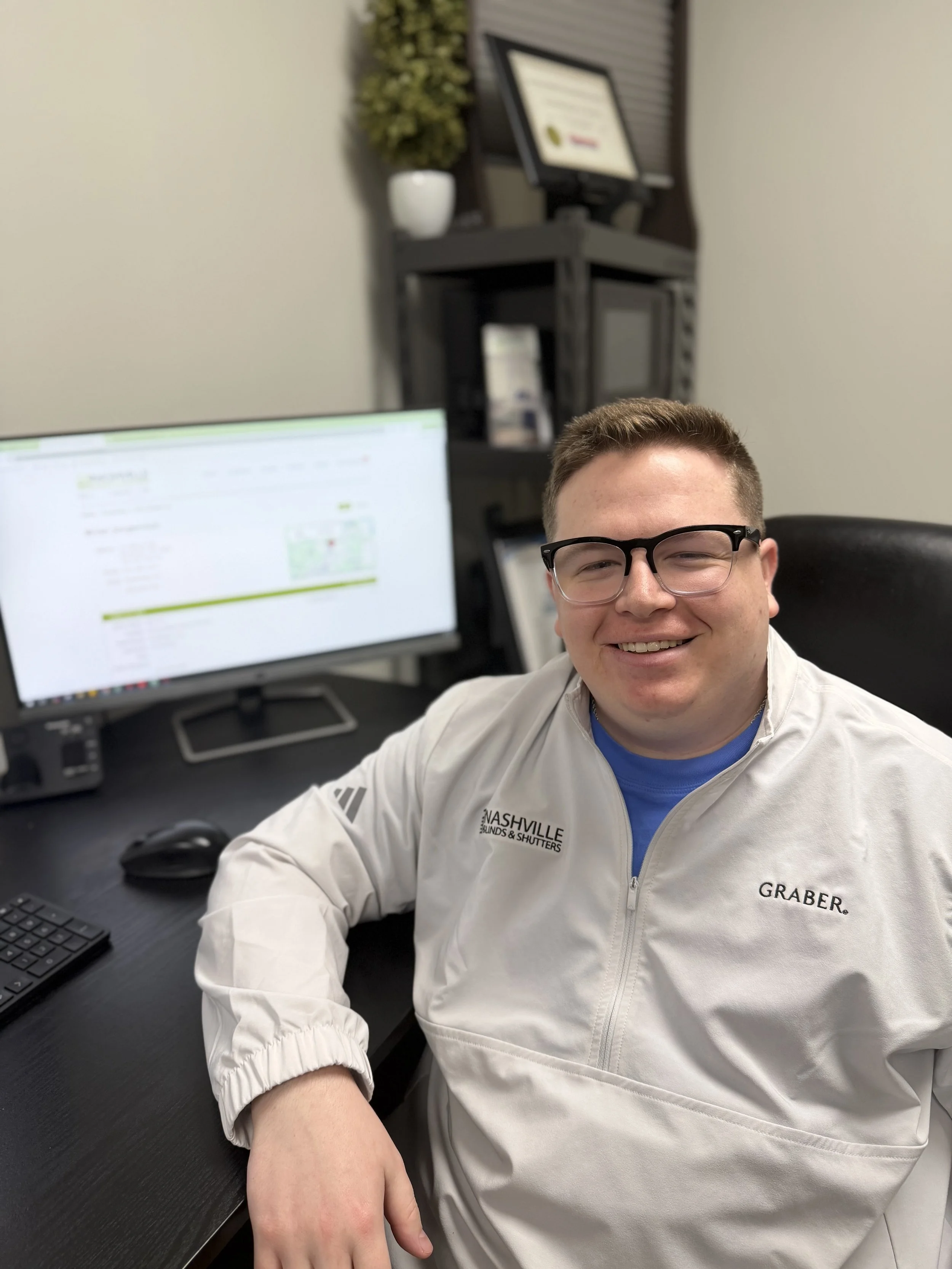 Kale, a Nashville Blinds & Shutters admin worker, sitting at his desk with a computer.
