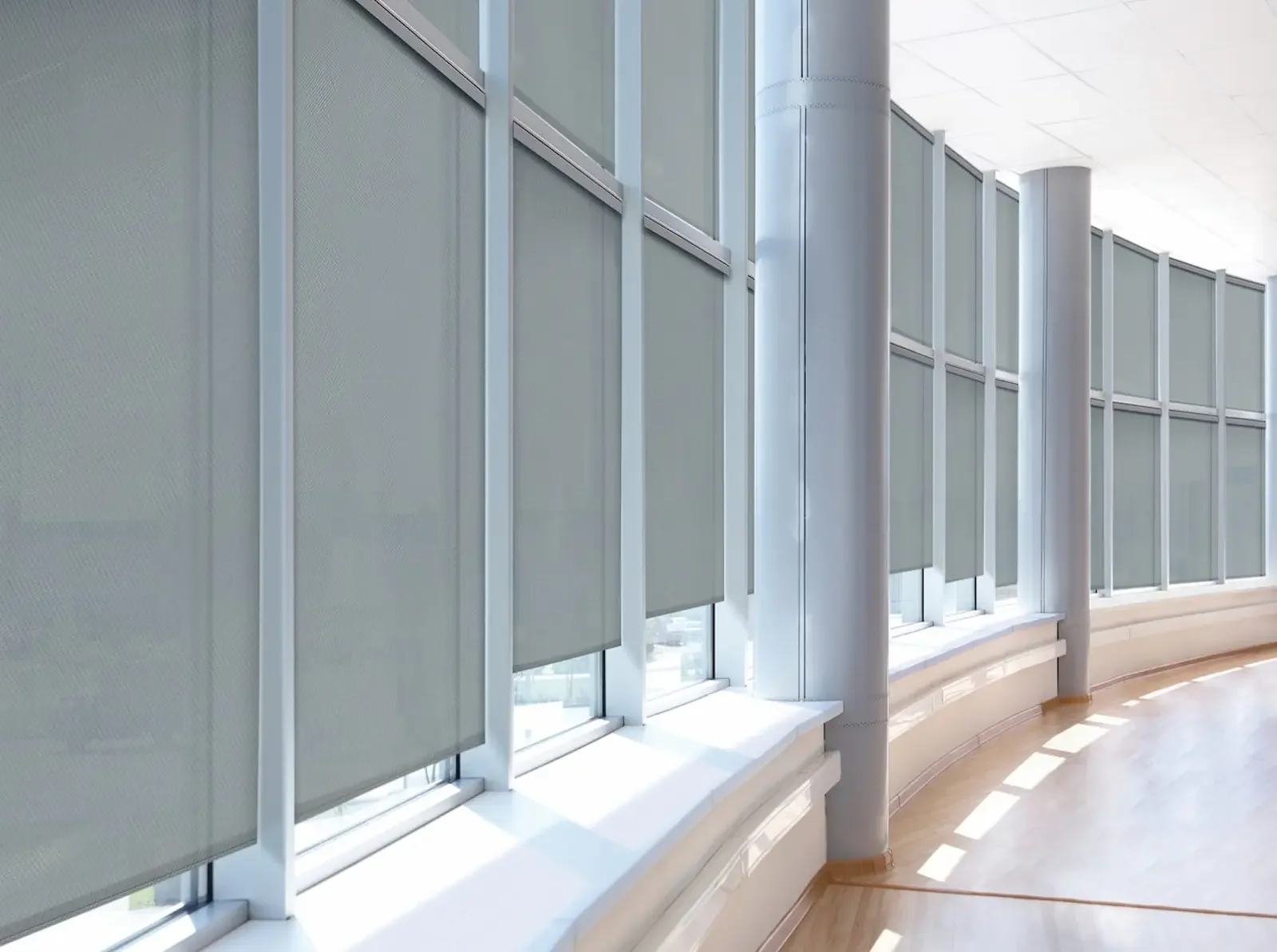 Heavy-duty solar roller shades mounted on tall commercial windows